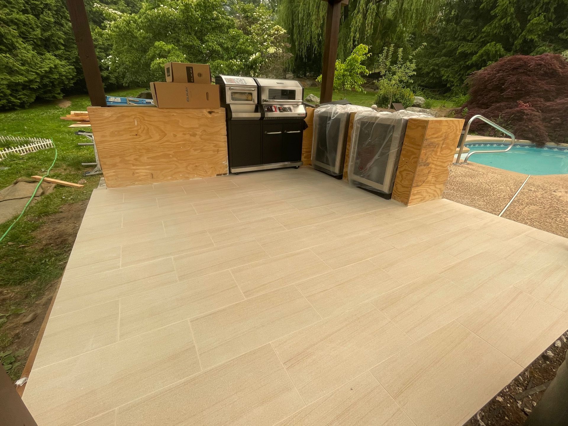 a patio with a grill and a pool in the background