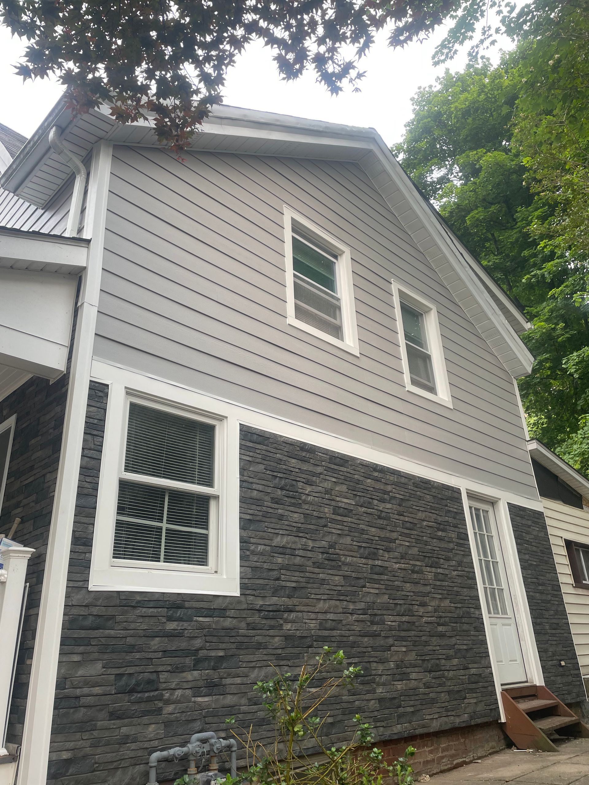 a house with gray siding and a black stone facade