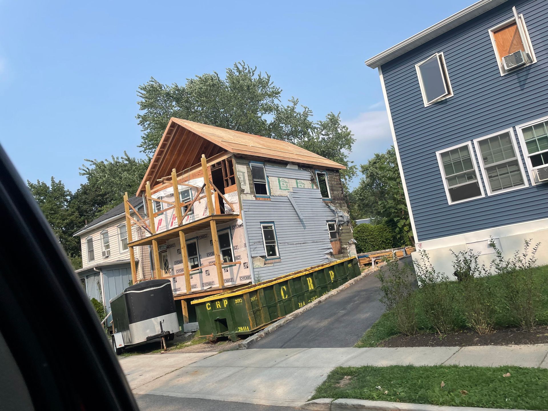 a house is being built on top of a green dumpster