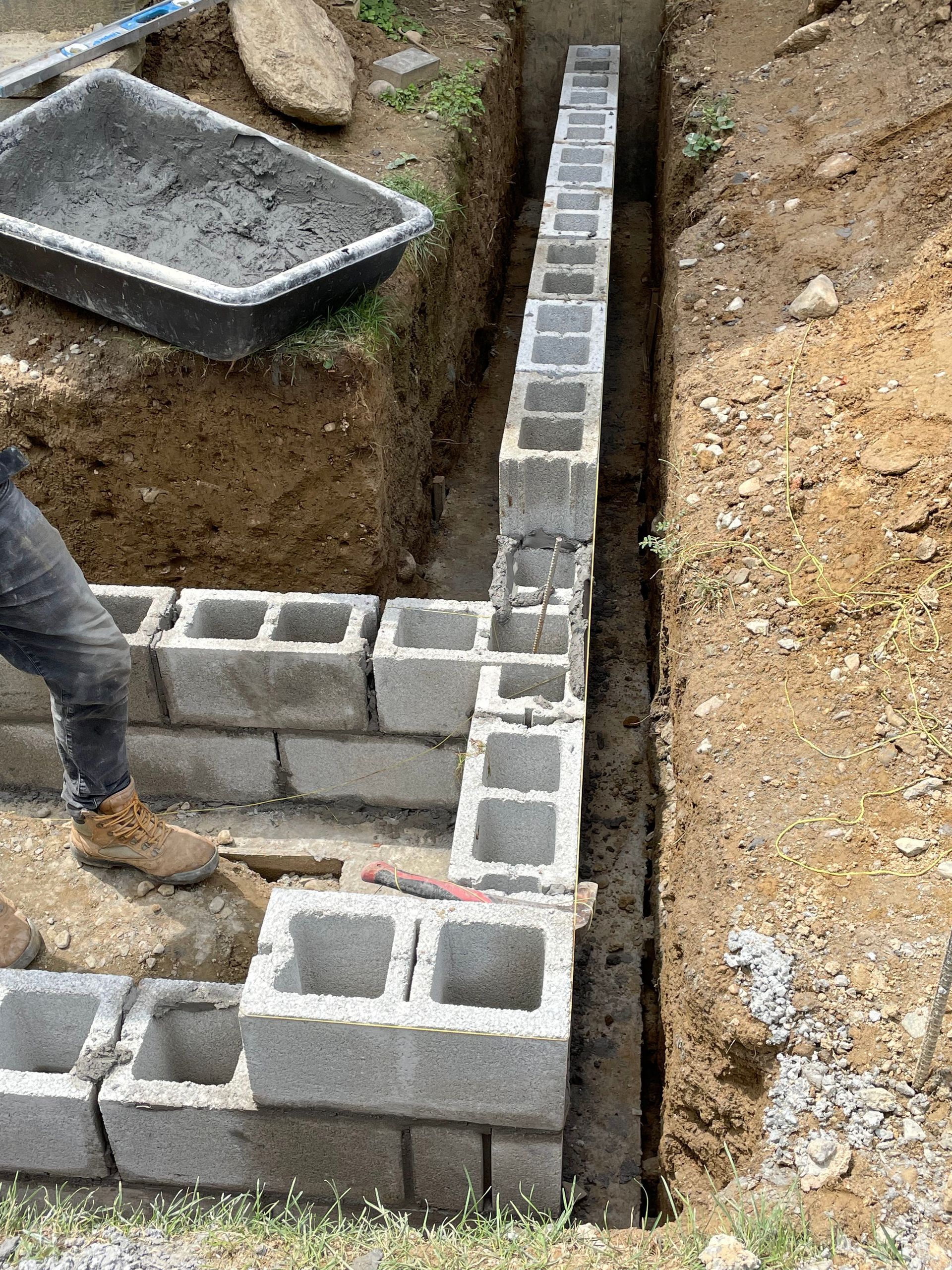 a man is laying concrete blocks in a trench