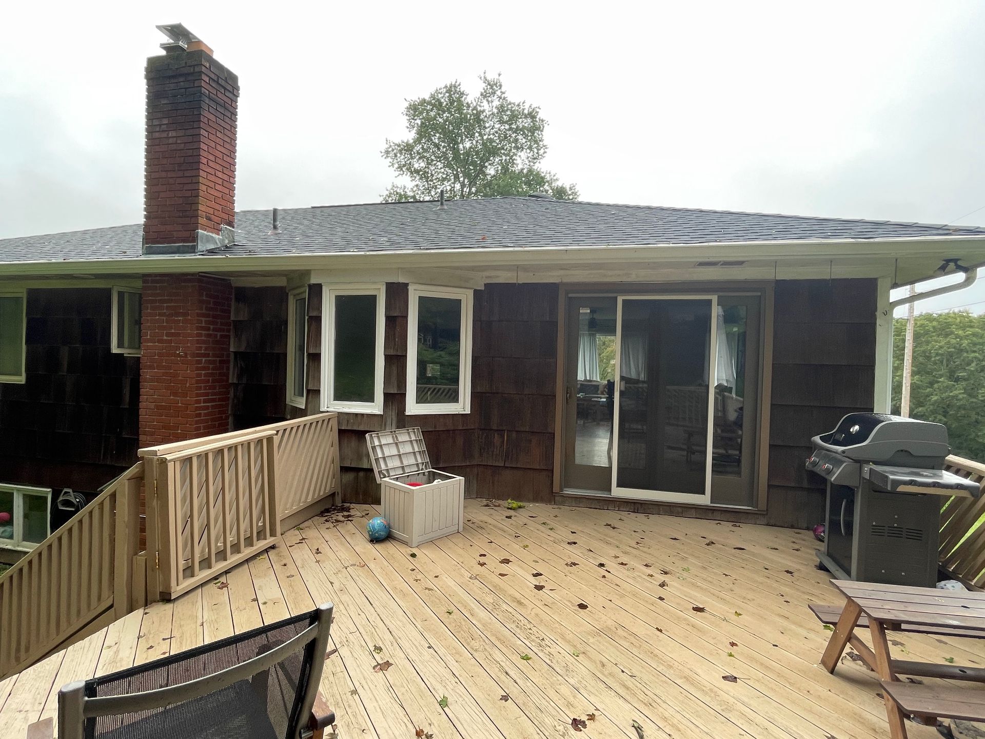 the back of a house with a wooden deck and a grill