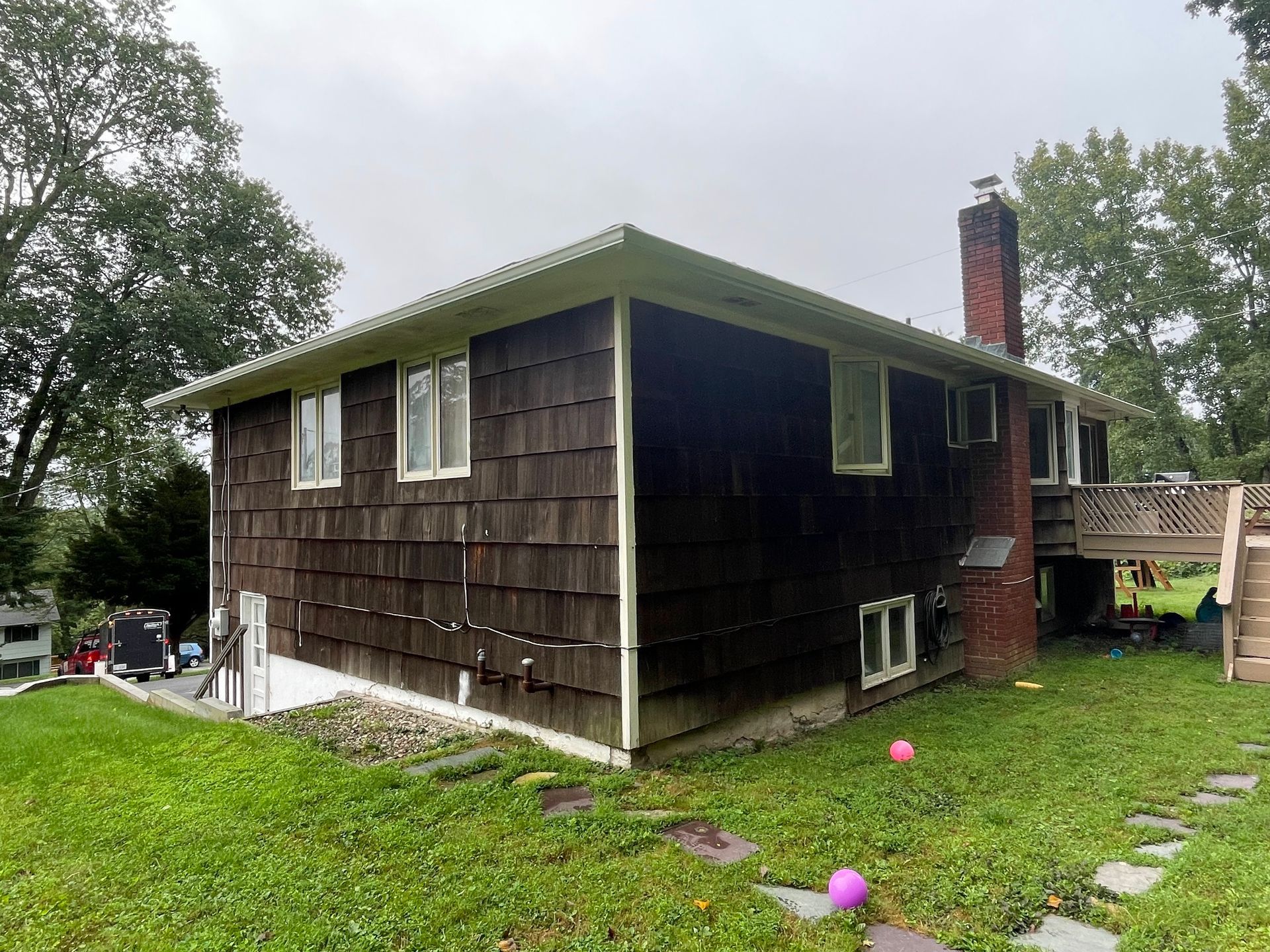 a house with a lot of windows is sitting on top of a lush green lawn