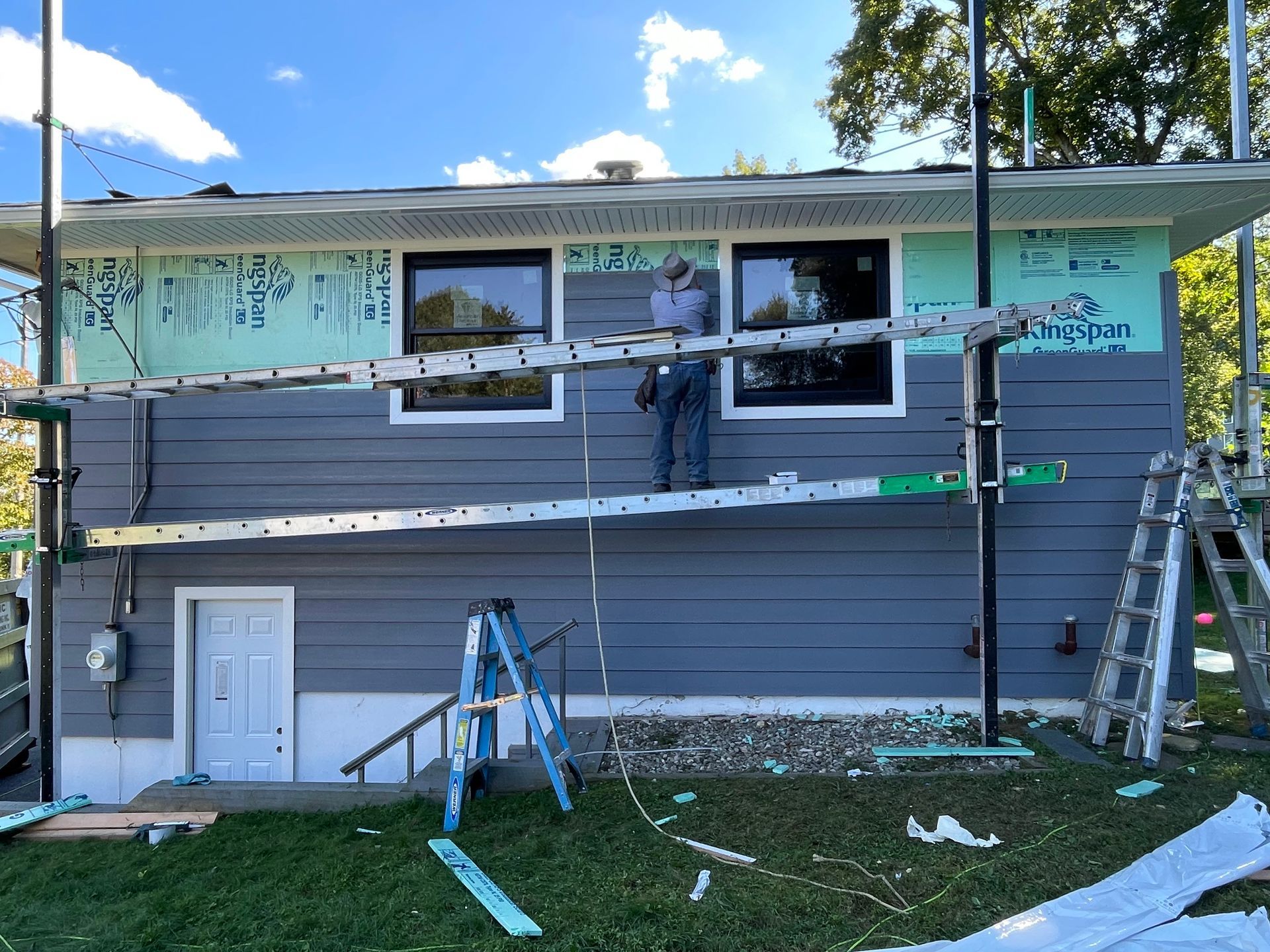 a man is standing on a ladder on the side of a house