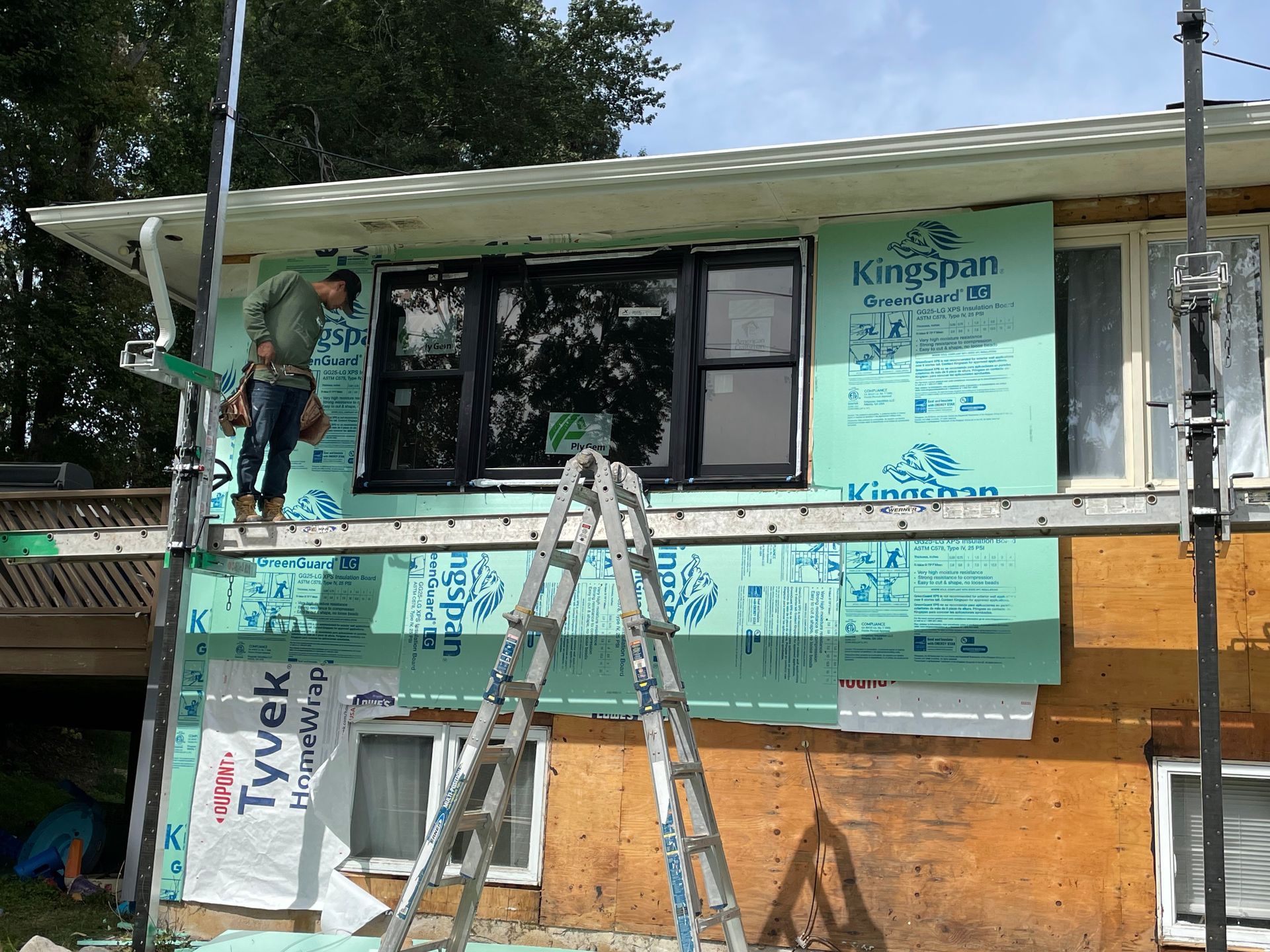 a man is standing on a ladder on the side of a house