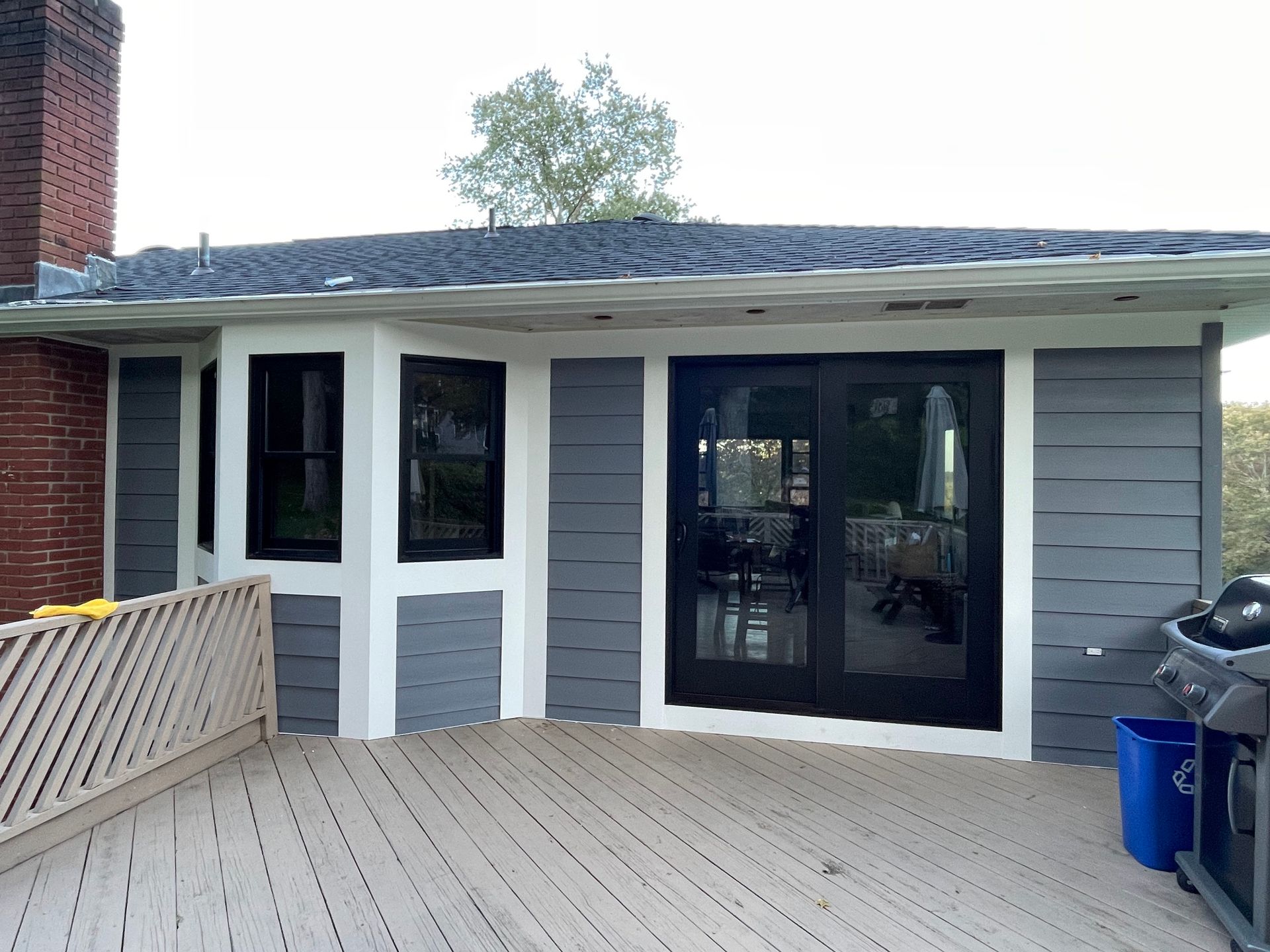a house with a deck and a grill in front of it
