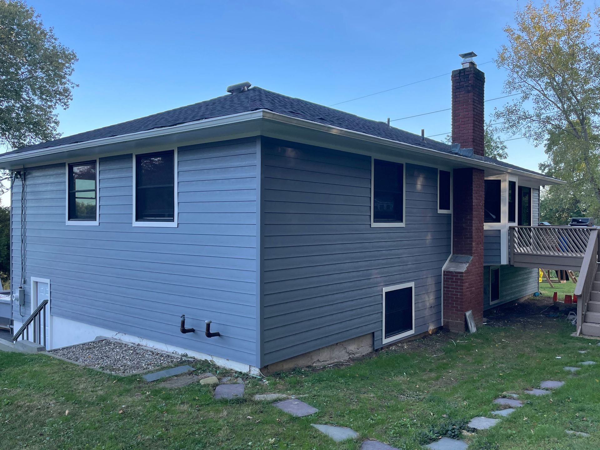 a blue house with a brick chimney and stairs in the backyard