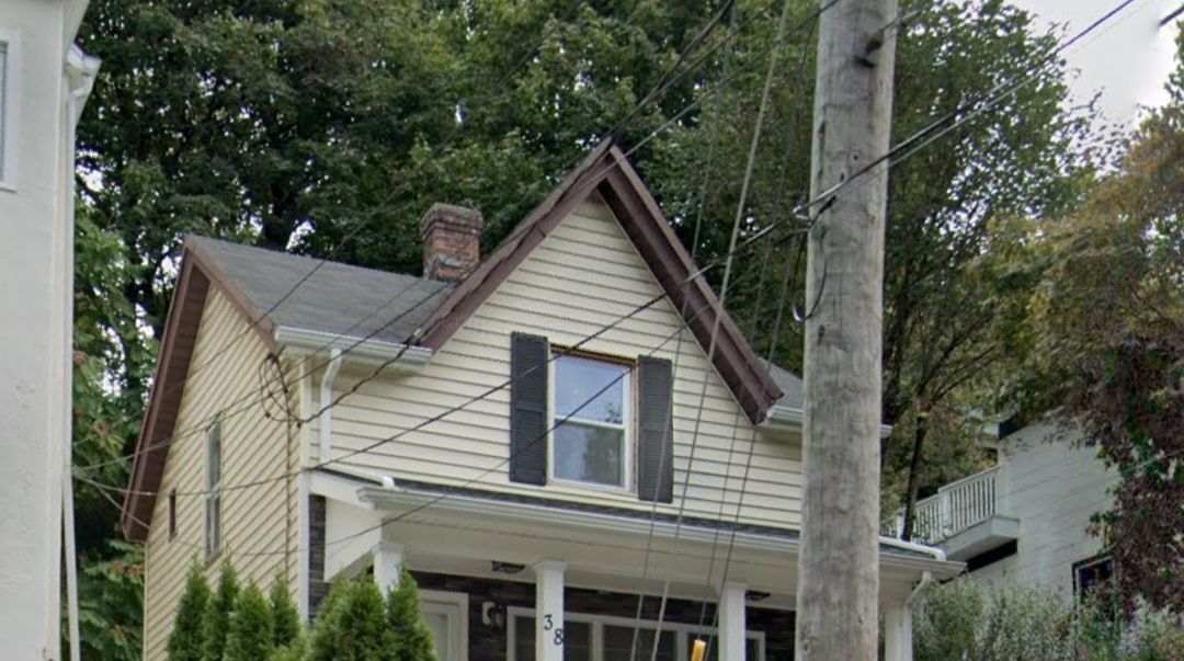 a small house with black shutters is sitting next to a power pole