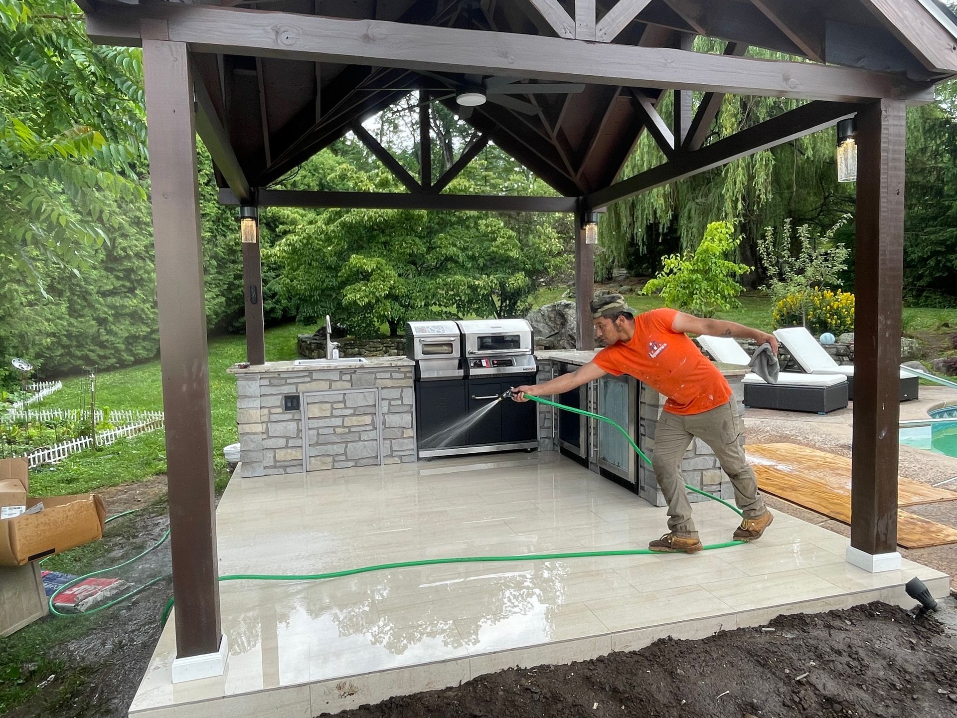 a man is spraying water on a patio under a gazebo