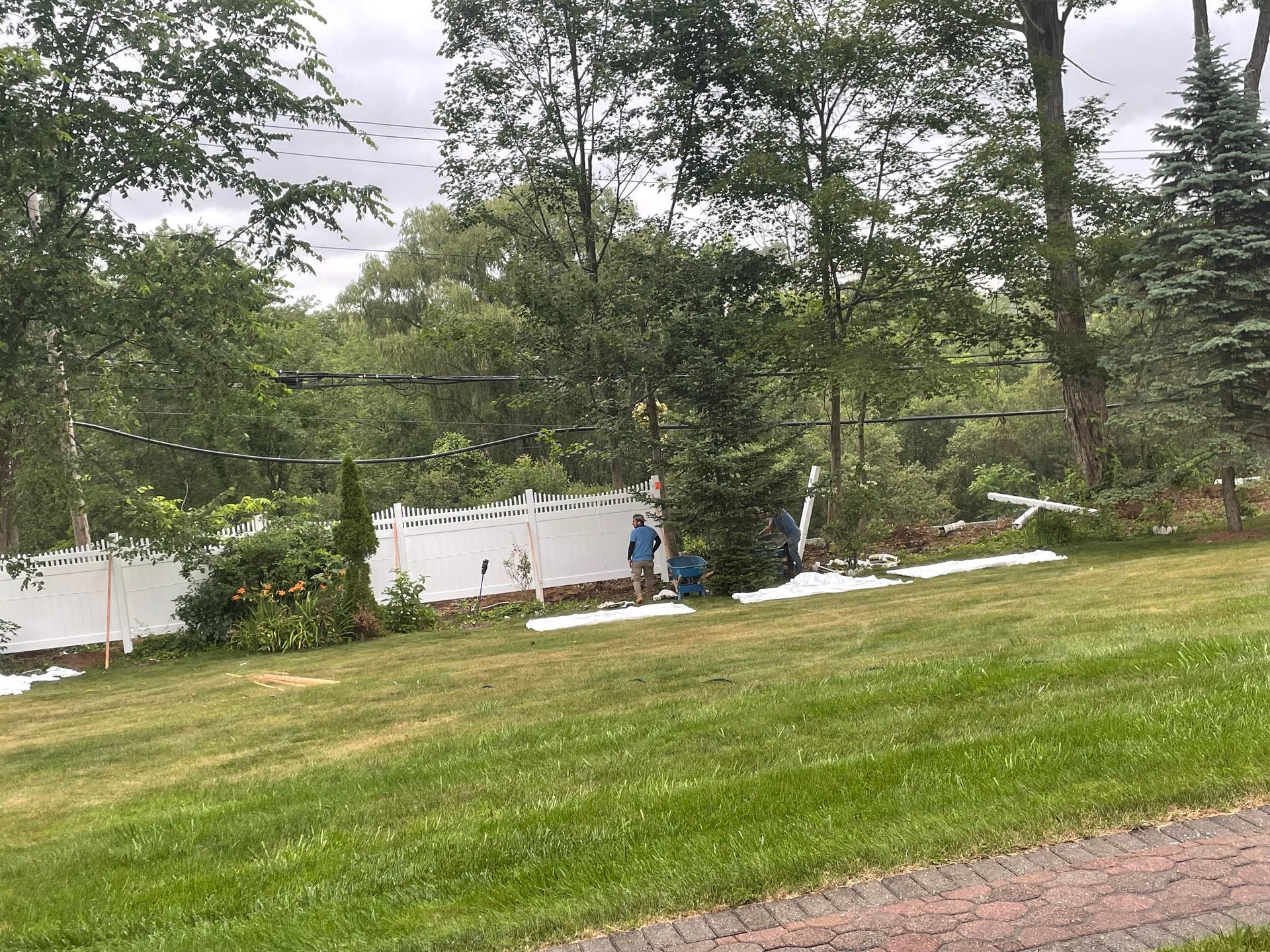a group of people are standing in a grassy field in front of a white fence