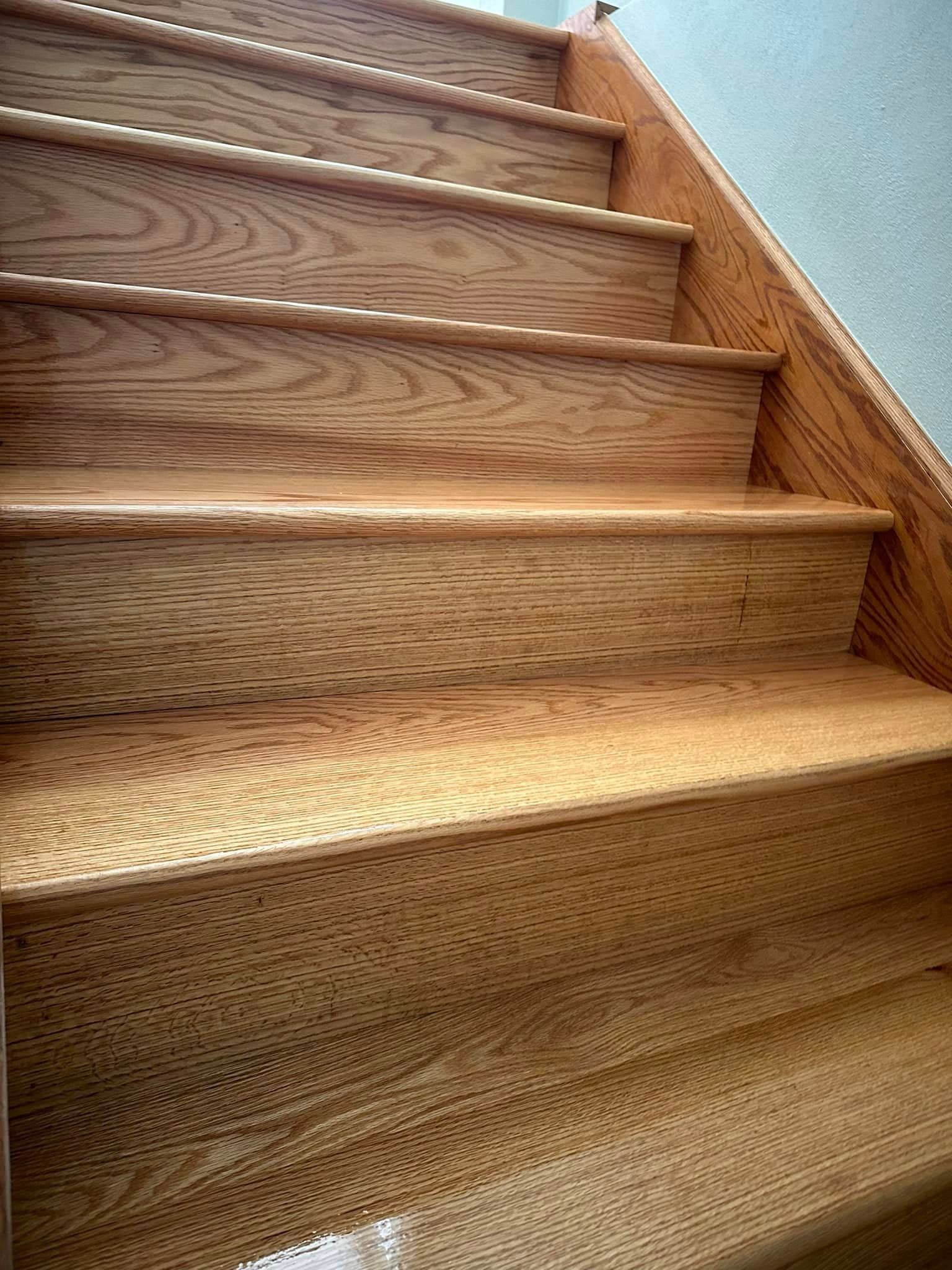 A close up of a wooden staircase with a wooden railing.