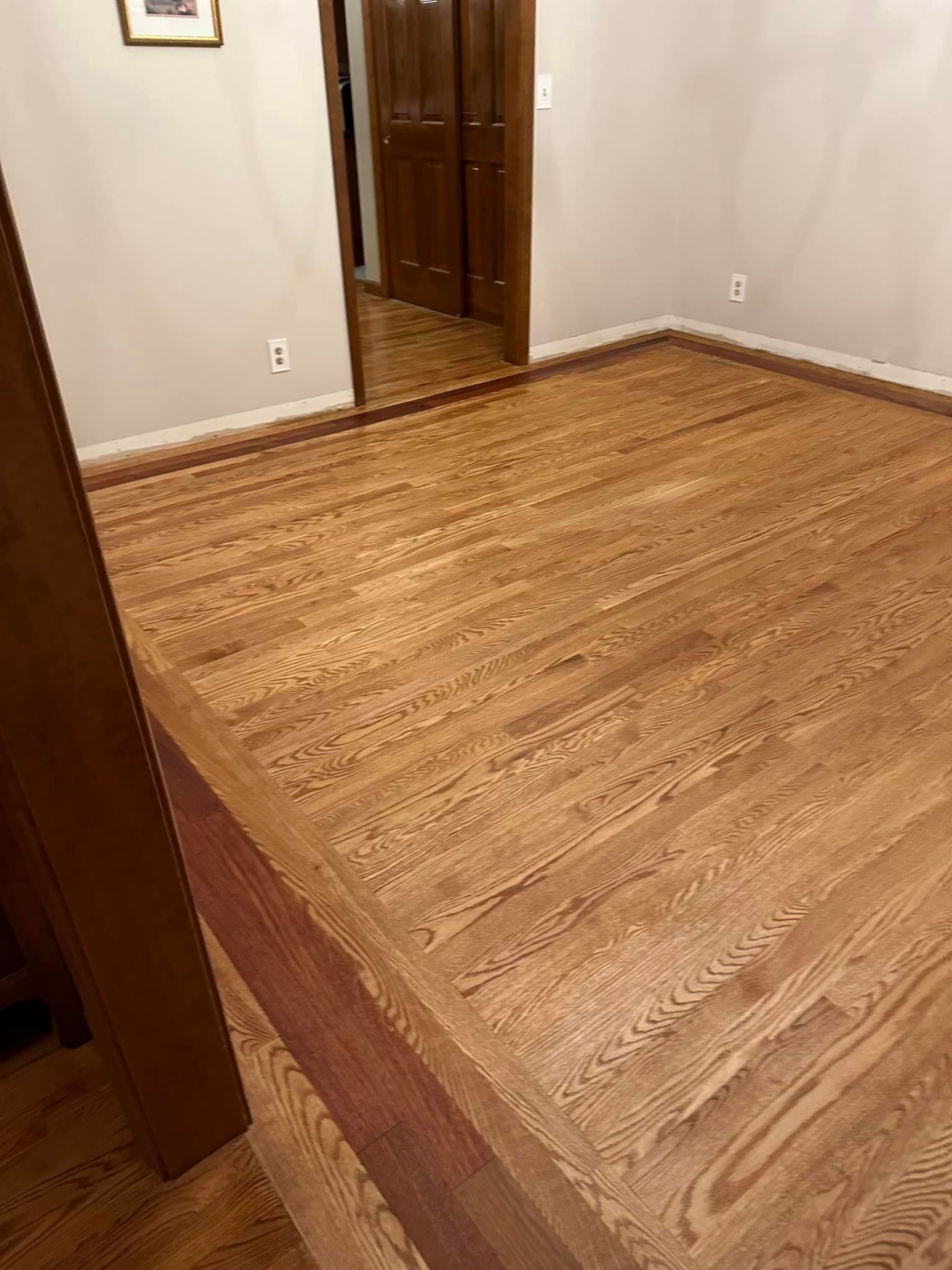 A room with hardwood floors and a mirror.