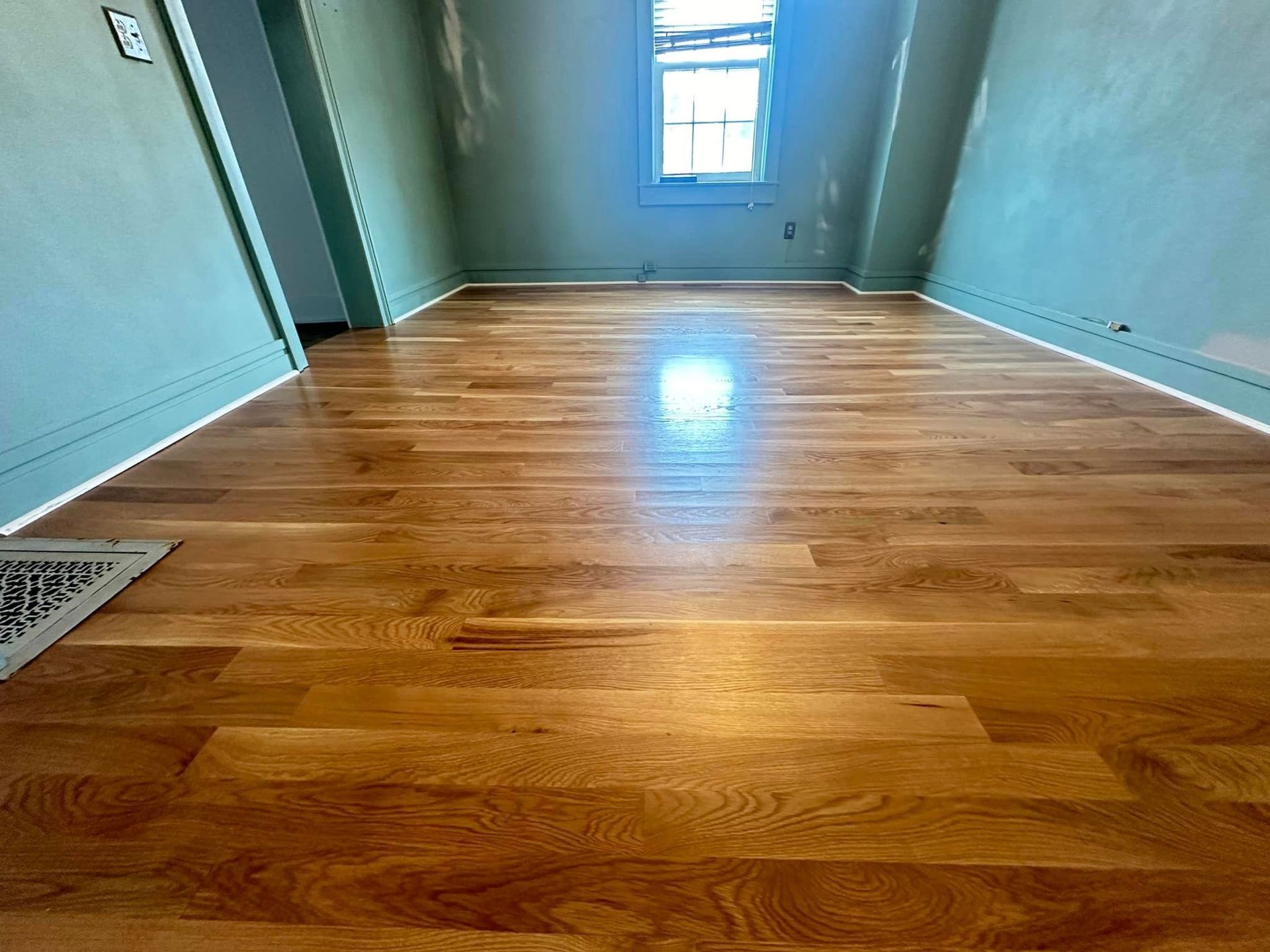A room with hardwood floors and a window.