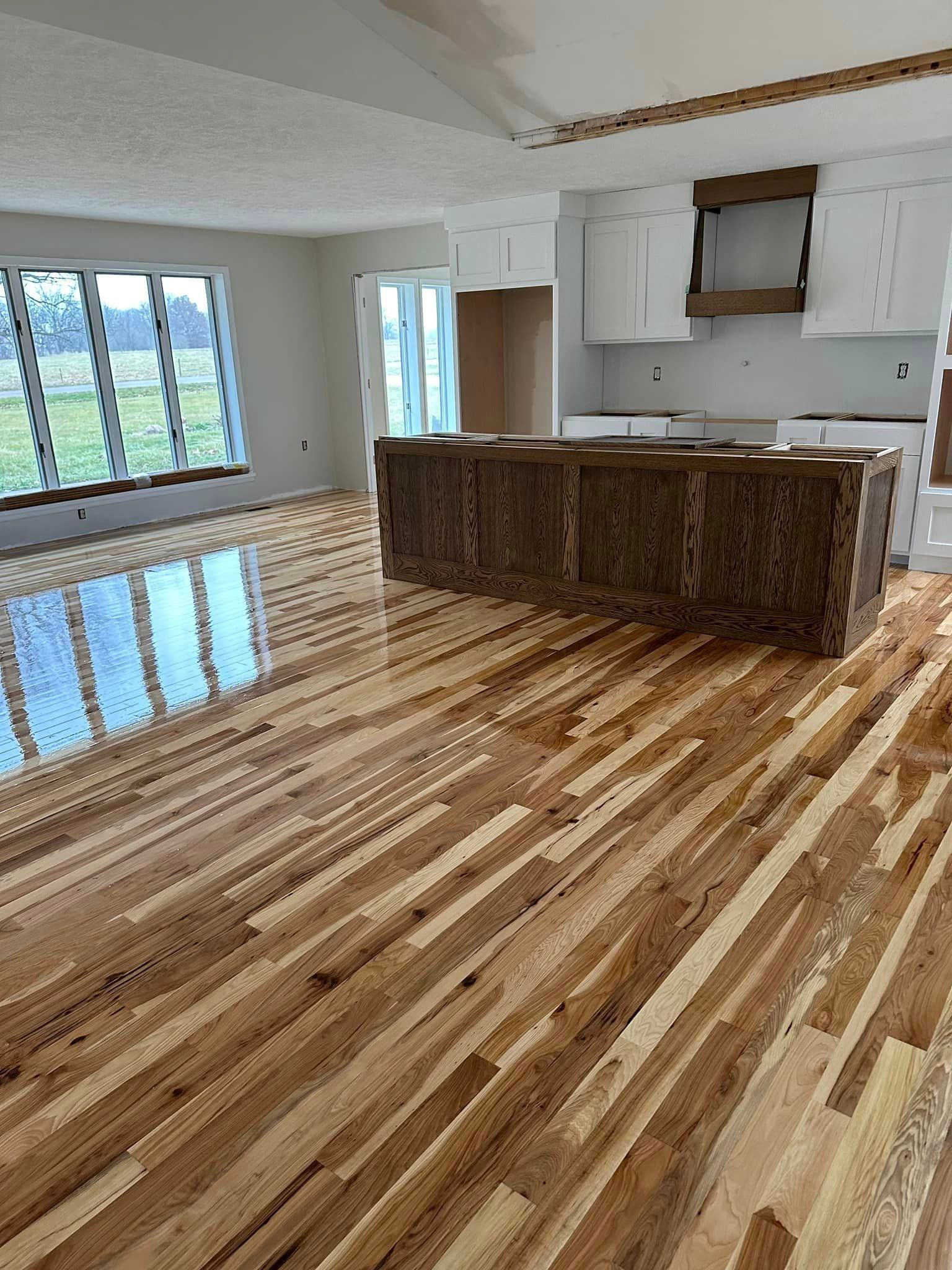 A living room with hardwood floors and a kitchen in the background.