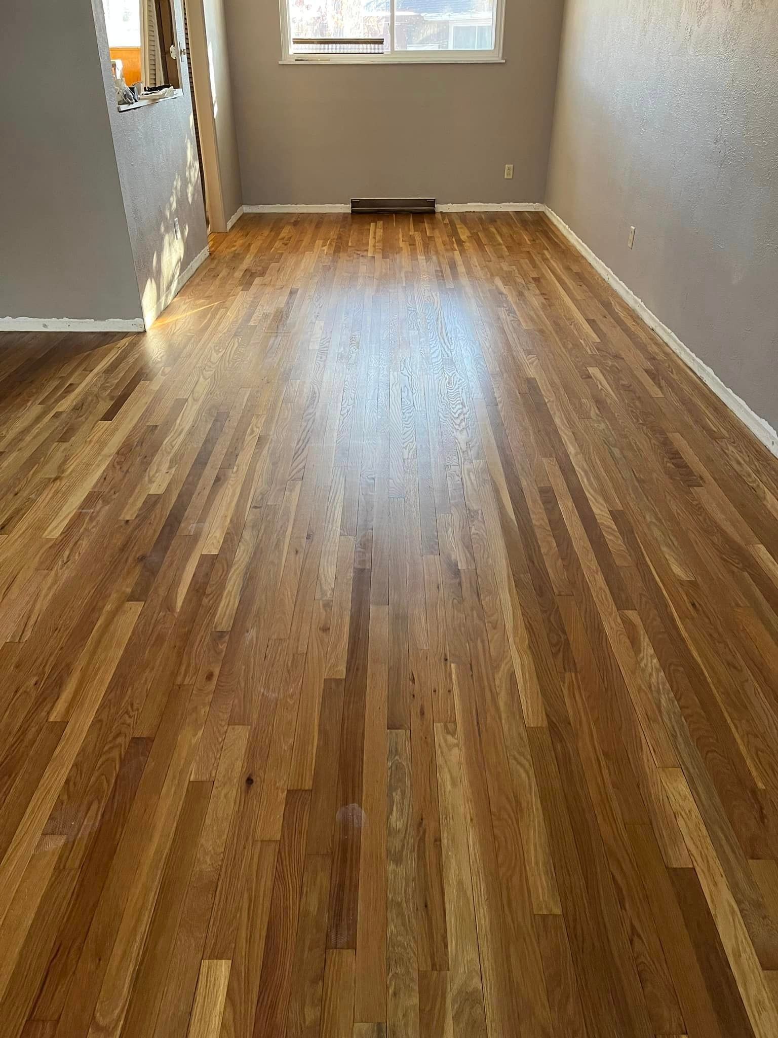 A living room with hardwood floors and a window.