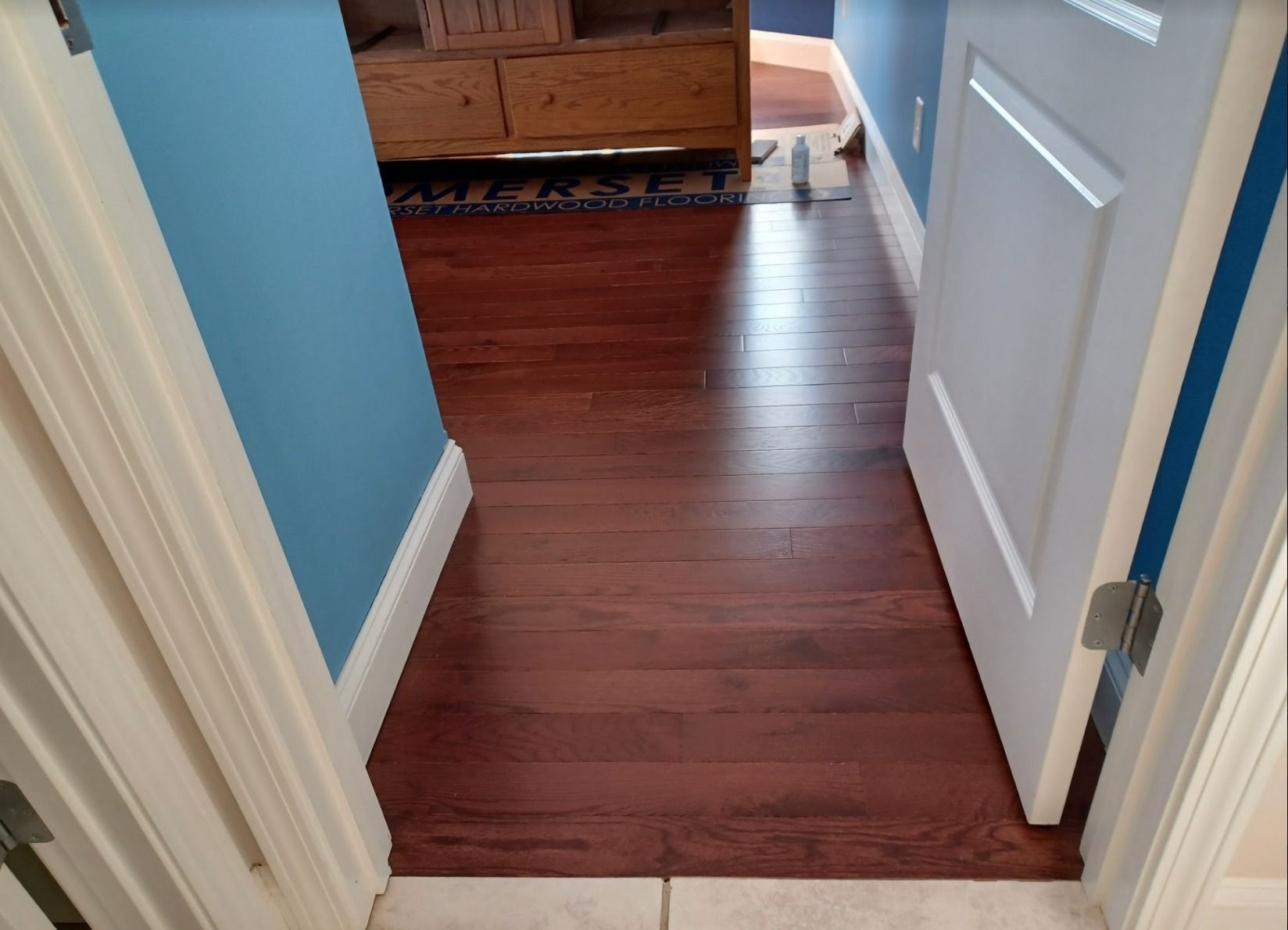 A hallway with hardwood floors and blue walls.