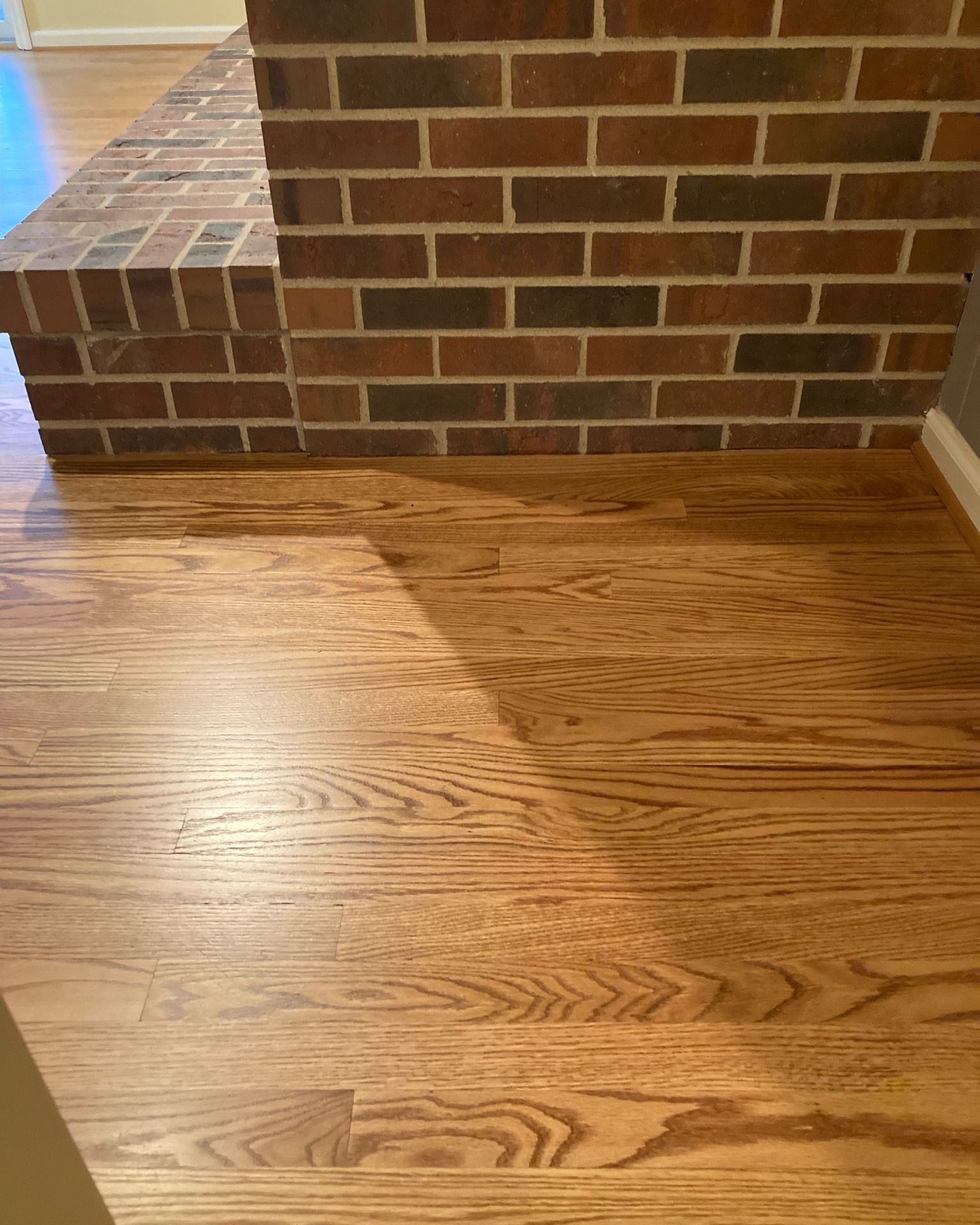 A wooden floor next to a brick wall in a room.