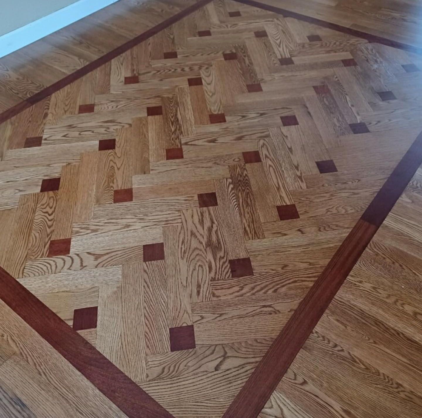 A wooden floor with a herringbone pattern and squares
