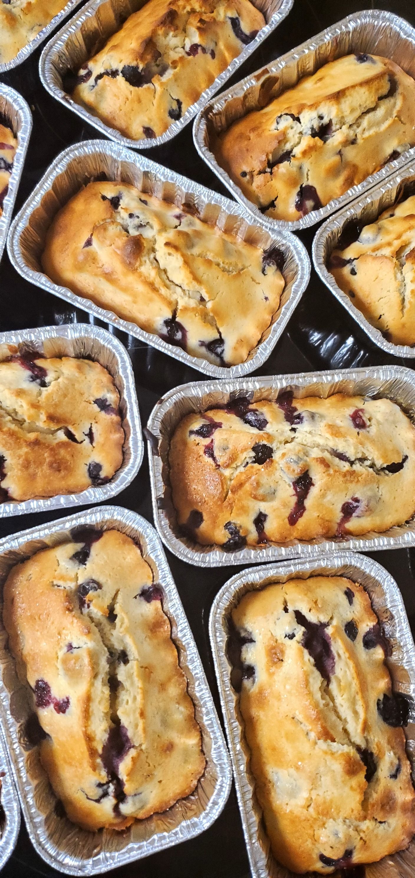 A bunch of baked goods in tin foil containers on a table.