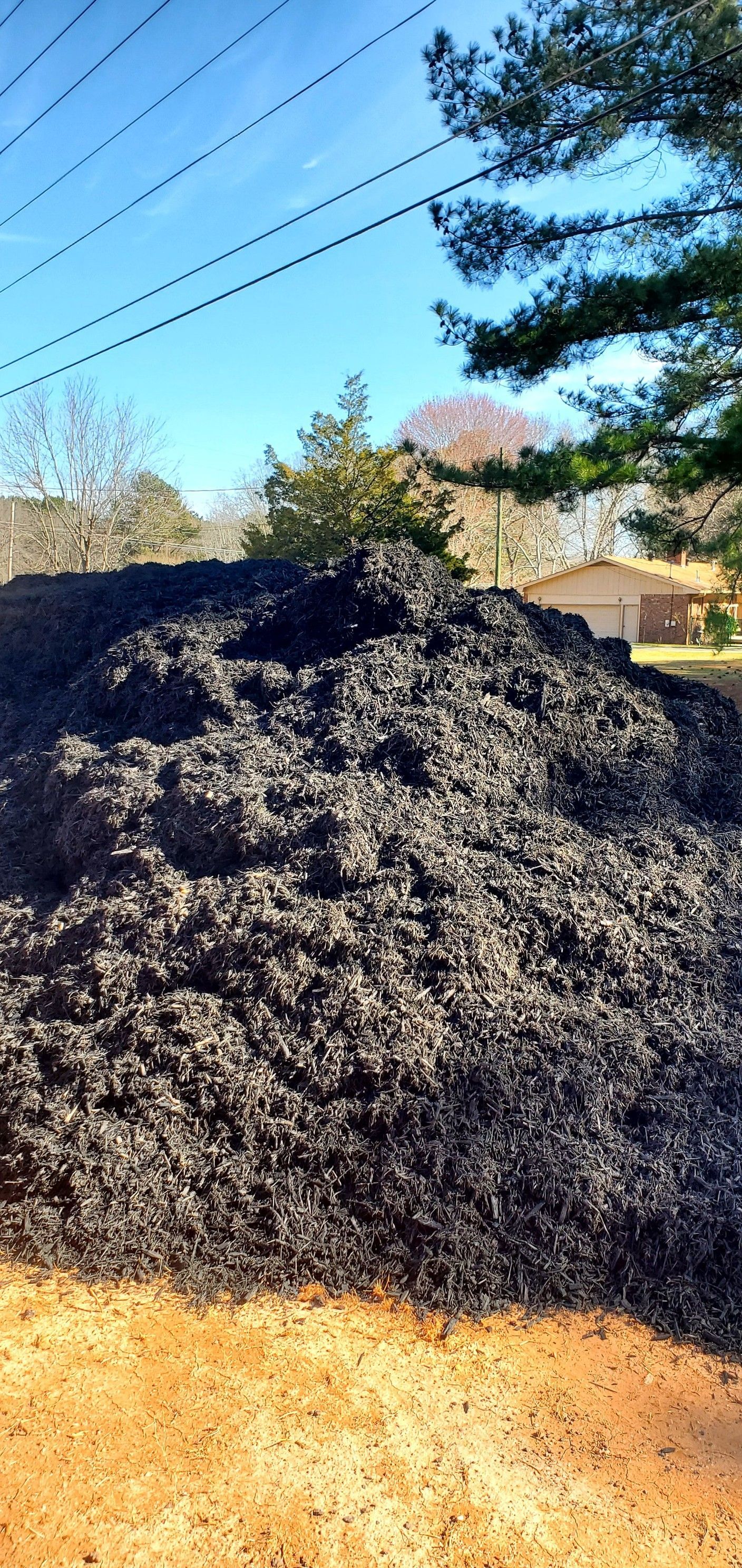 A large pile of coal is sitting on top of a dirt field.