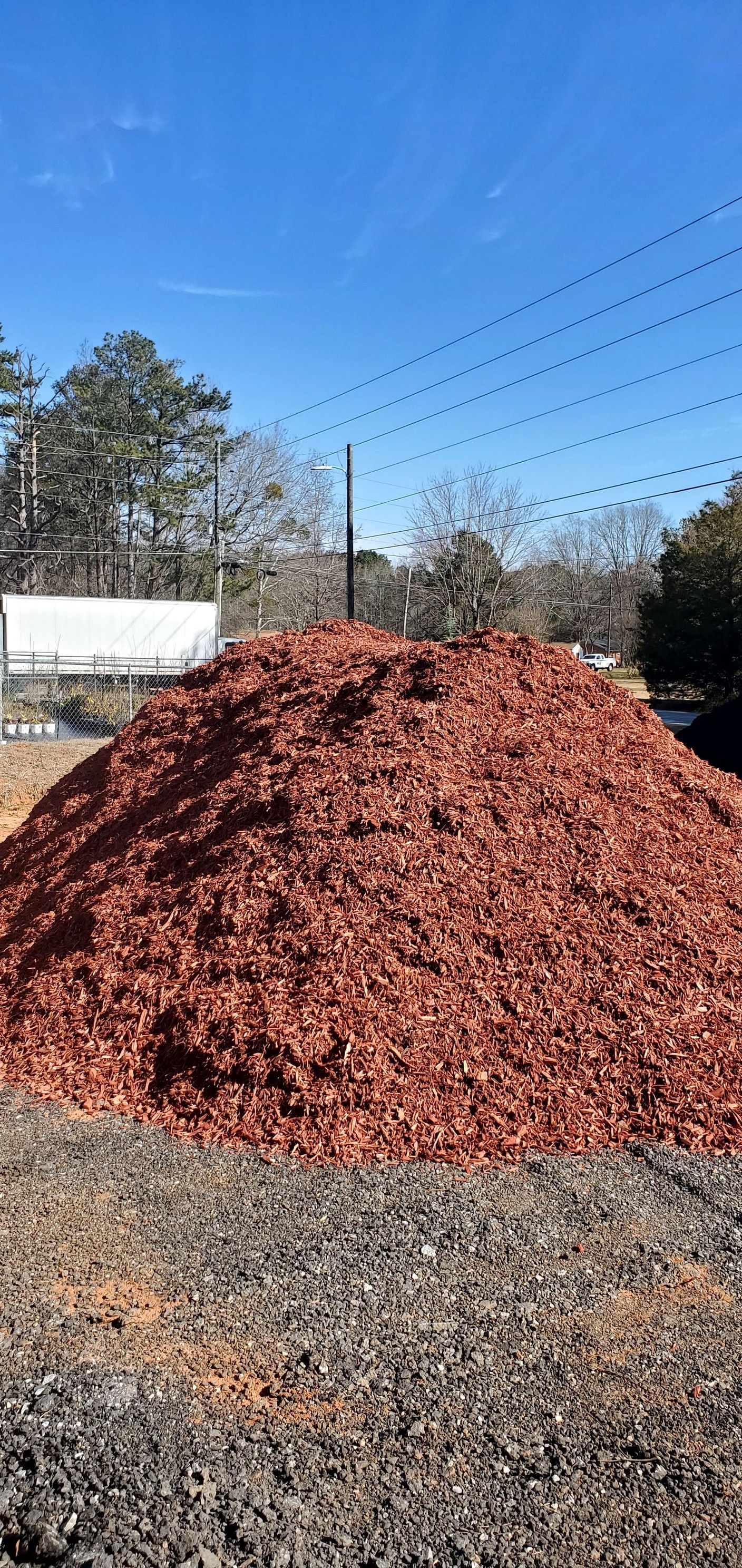 A pile of red mulch is sitting on top of a pile of gravel.