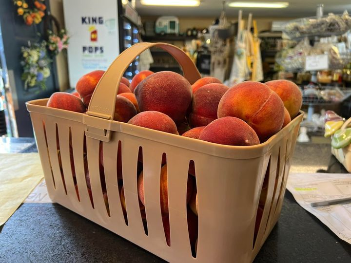 A basket of peaches is sitting on a table in a store.