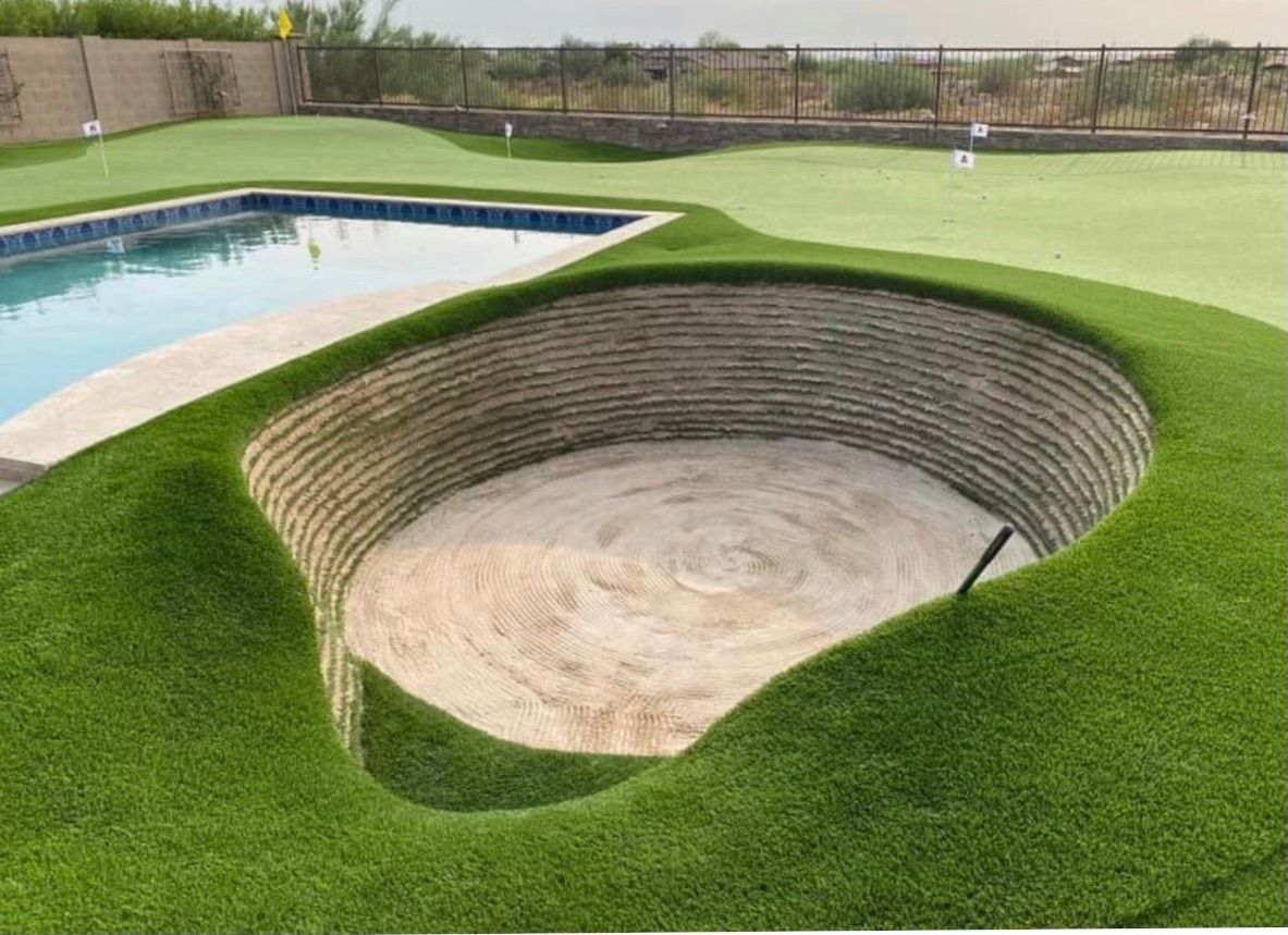 Backyard golf green and pool with sand trap. Artificial turf surrounds the green and pool.