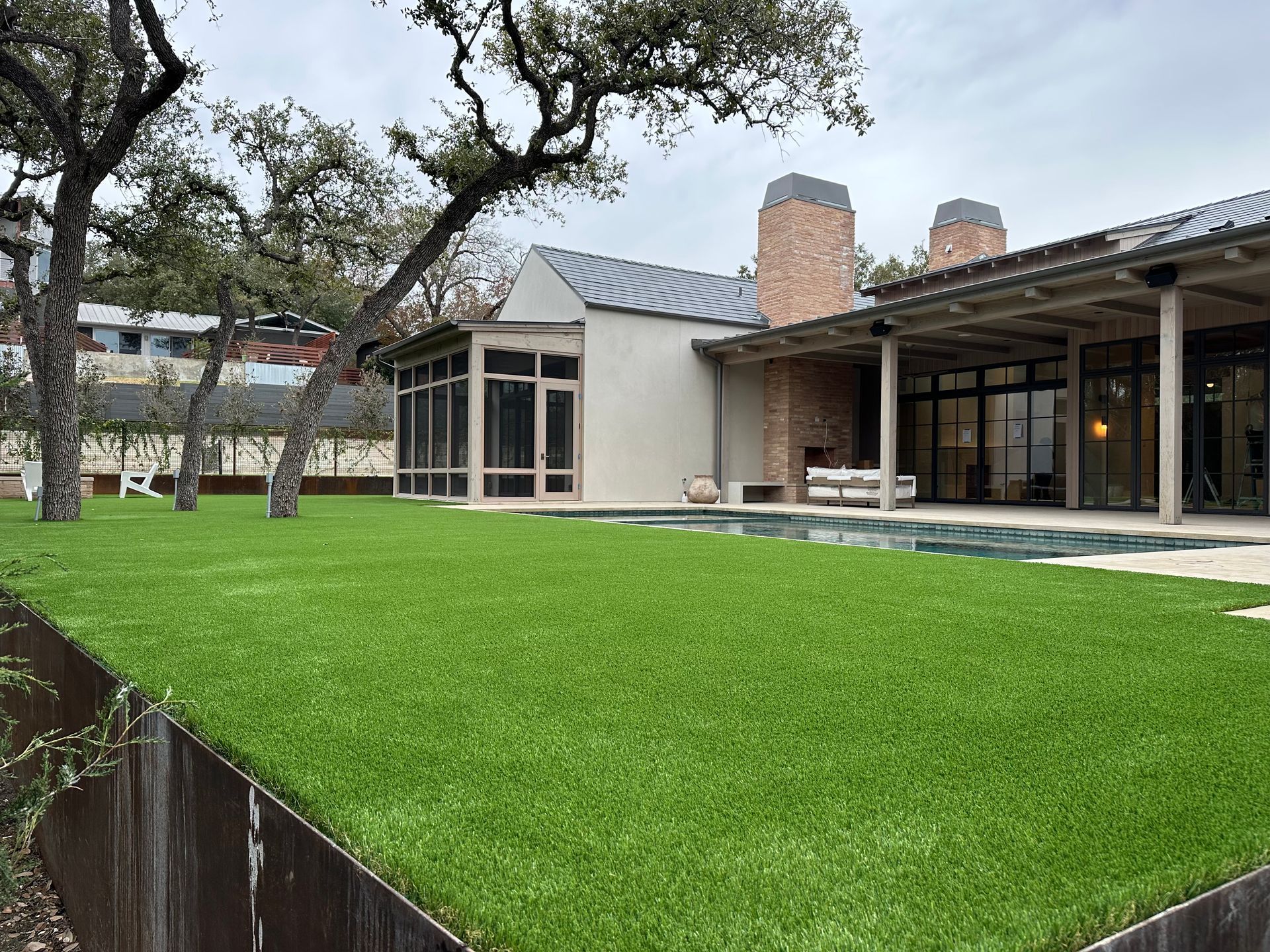 Green lawn, modern home with pool and patio.