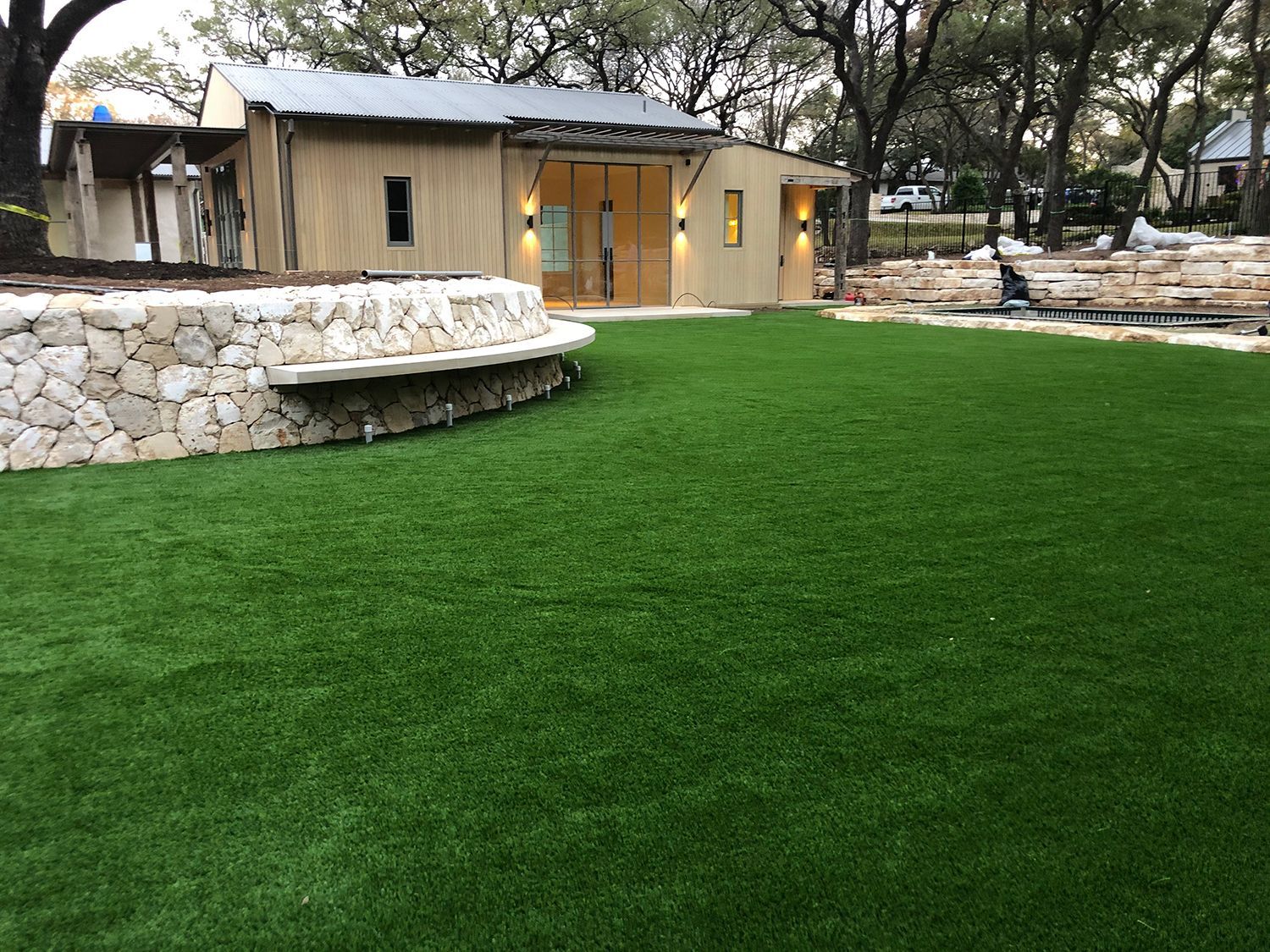 Exterior view of a building with stone wall and green lawn.