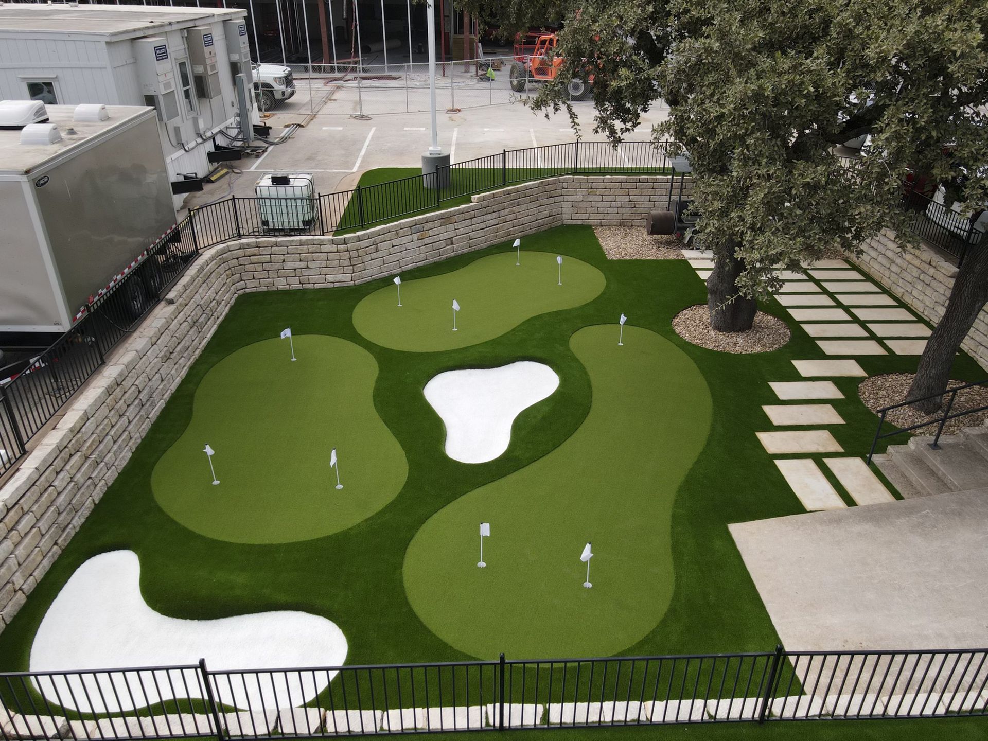 Miniature golf course with green turf, white sand traps, and stone walkway.
