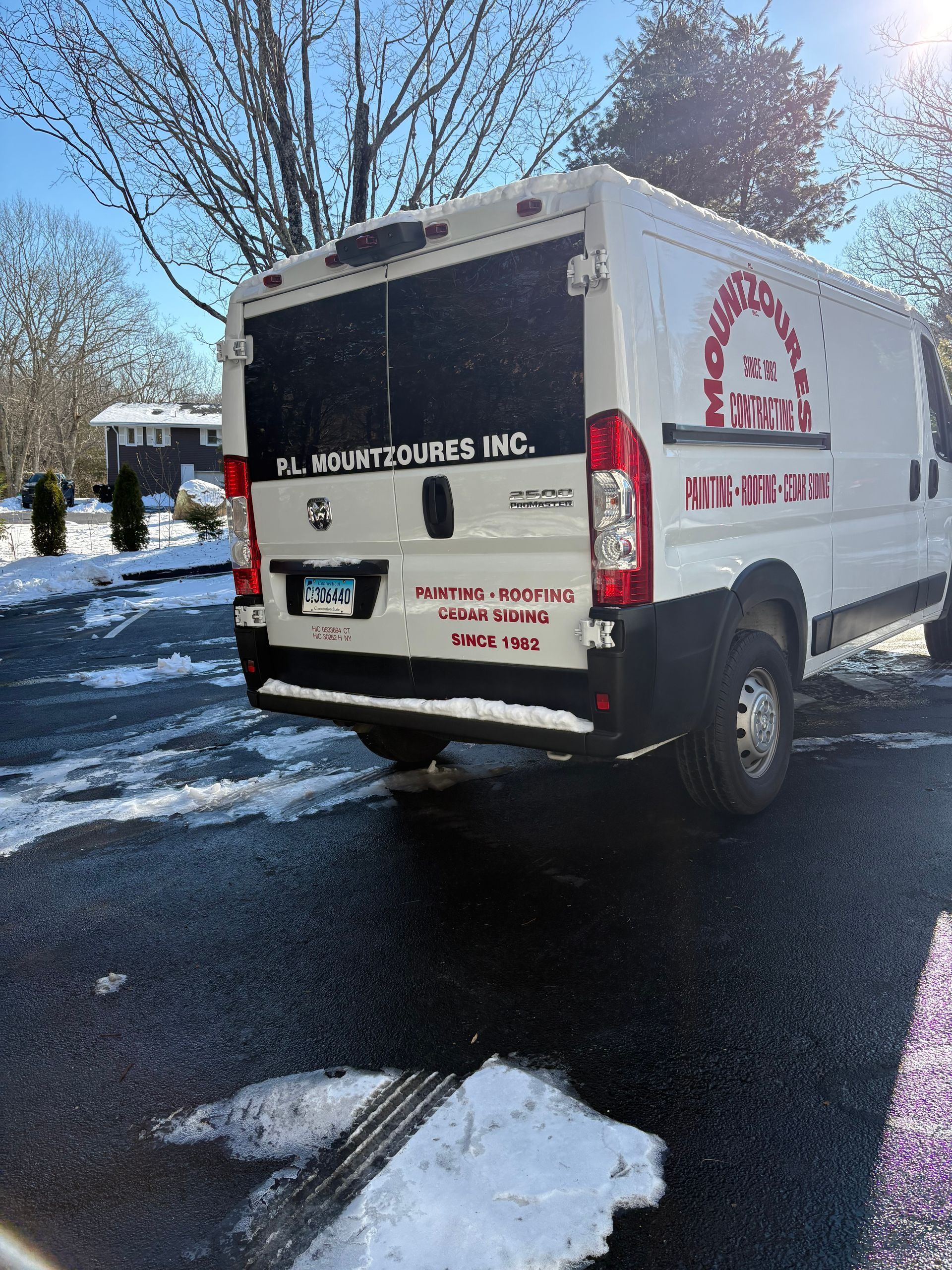 White van with company logo parked on snowy asphalt.