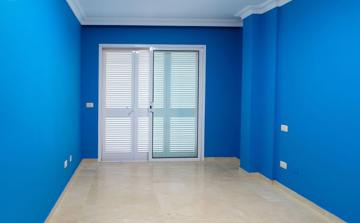 Empty room with blue walls, white door, and tiled floor