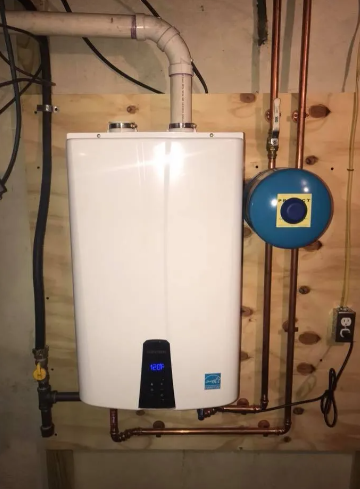 A tankless water heater mounted on a wooden wall, connected to copper piping, a blue expansion tank, and a white vent pipe.