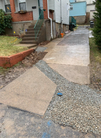 A residential driveway showing a section of concrete pavement transitioned with gravel leading to the house steps.