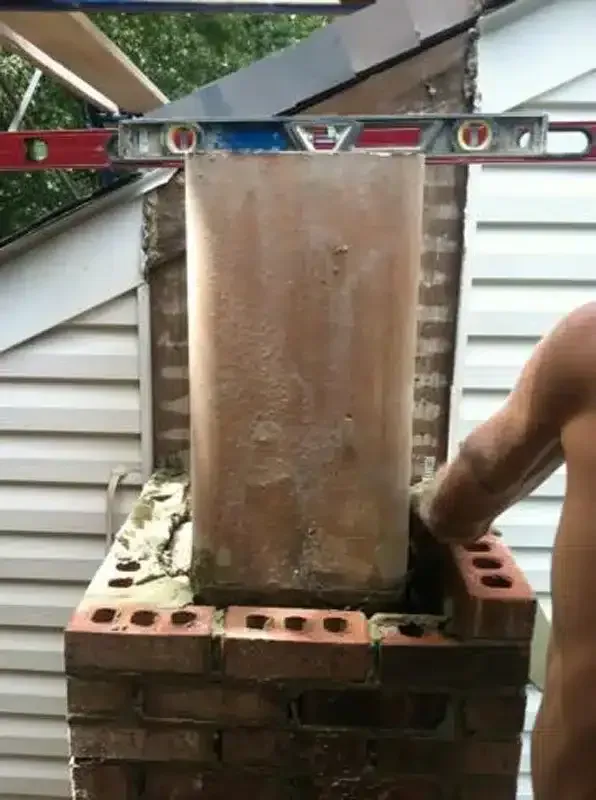 Level on brick column with a person’s arm adjusting it outdoors