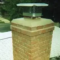 Brick chimney with a metal cap on a tiled rooftop outdoors