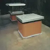 Two square concrete pedestals on a wet floor in a dark room, one with a metal frame above it