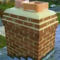 Brick chimney with a metal cap on a rooftop