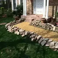 Front porch with a stone-bordered gravel pathway and brick house steps