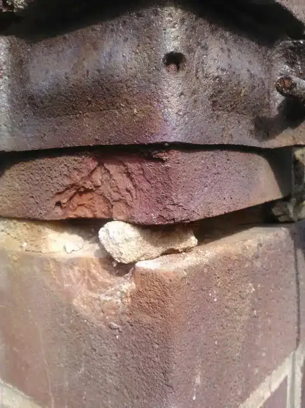 Close-up of a rusty, damaged metal surface with a cracked seam and chipped paint