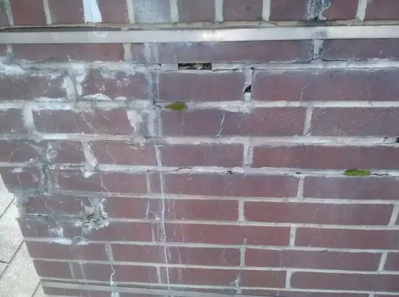 Close-up of a red brick wall with white paint stains and worn mortar lines