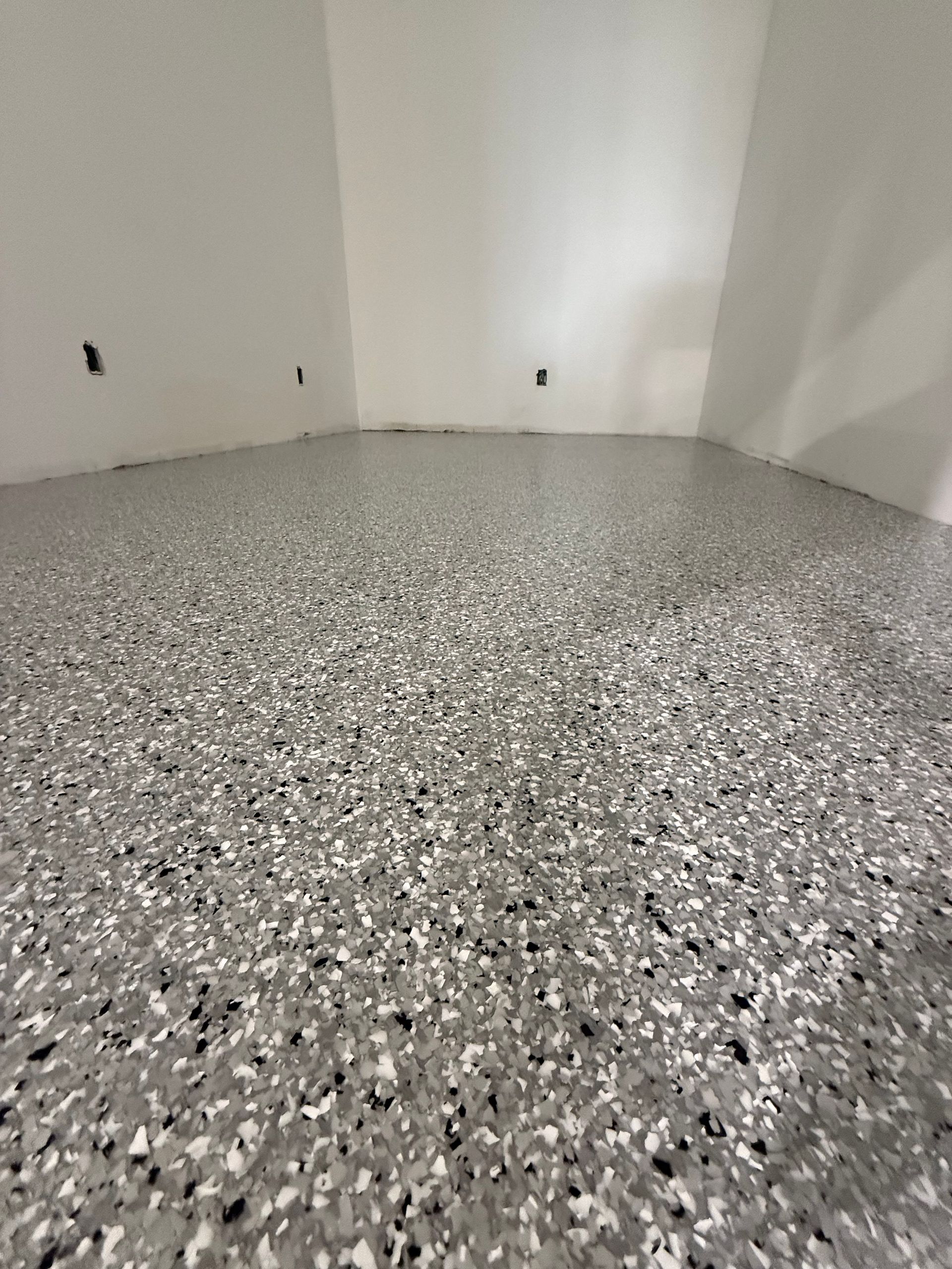 Empty room with white walls and a gray speckled epoxy floor
