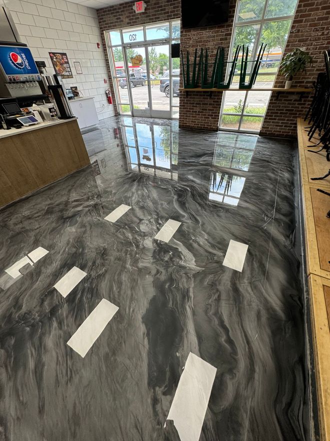 Marble-look floor in a modern lobby with sunlight, glass doors, brick walls, and counter seating