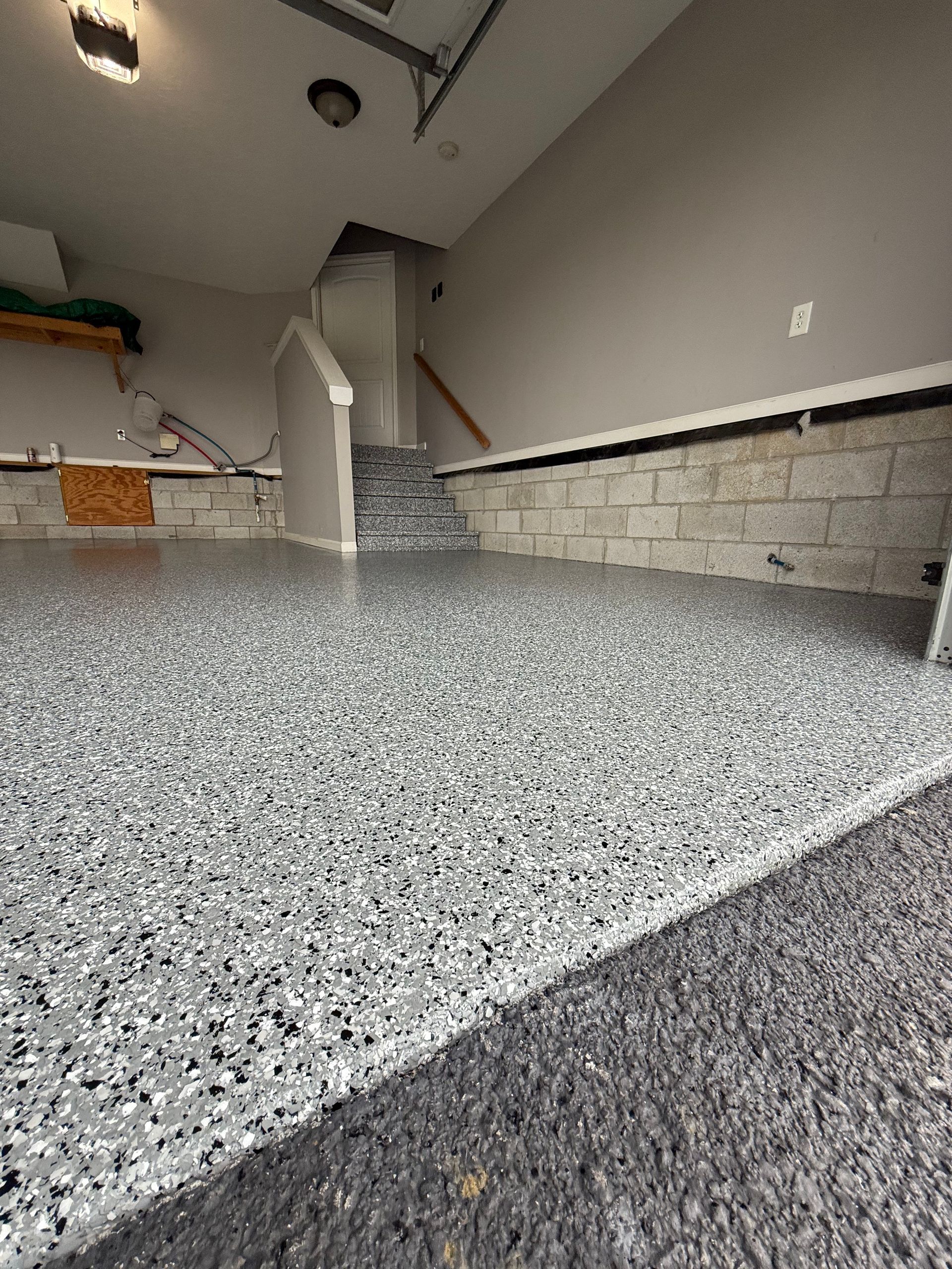Empty kitchen with speckled countertop, gray tile backsplash, and white cabinets under renovation.