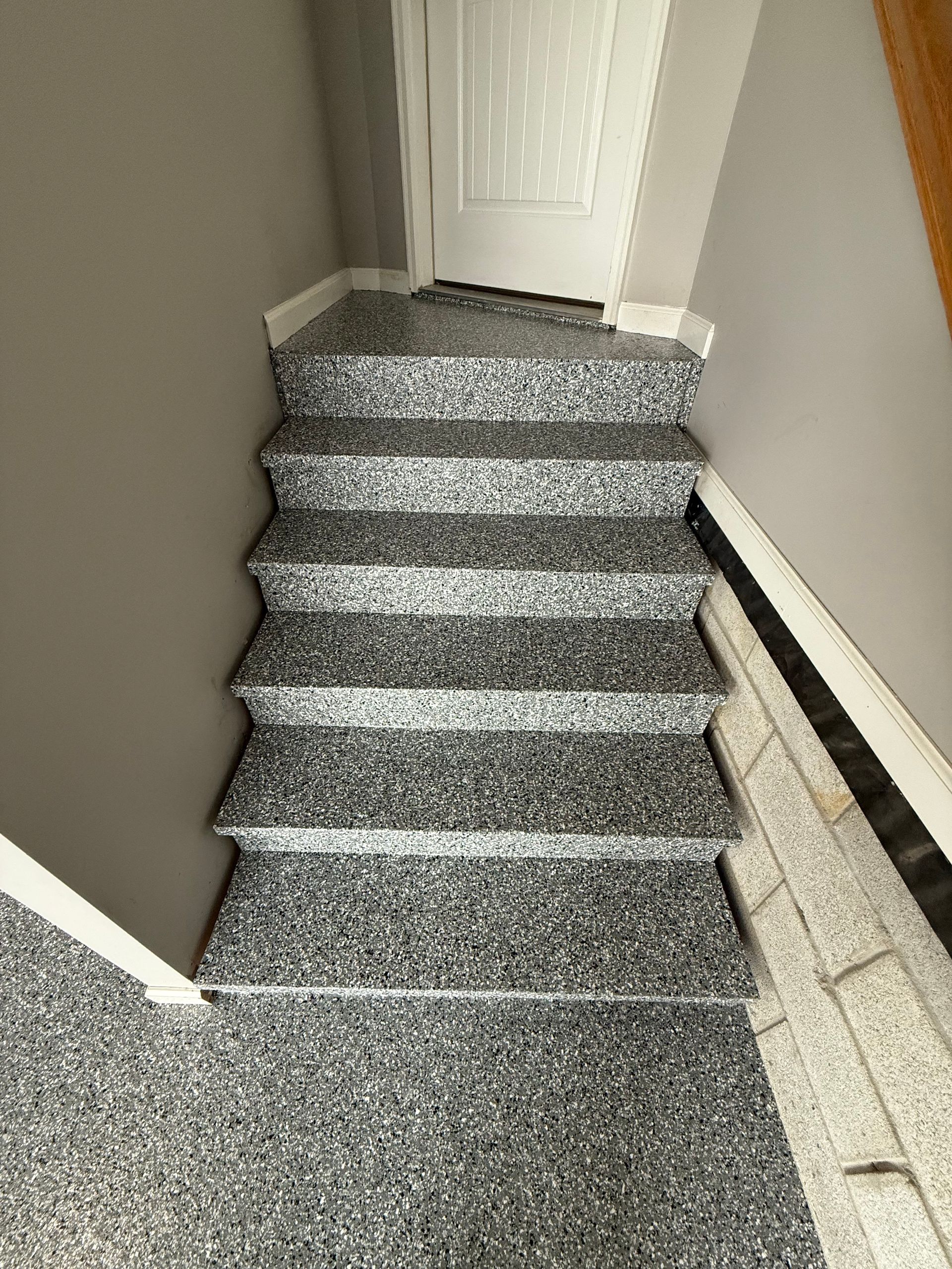 Narrow carpeted stairway leading up to a white door in a hallway