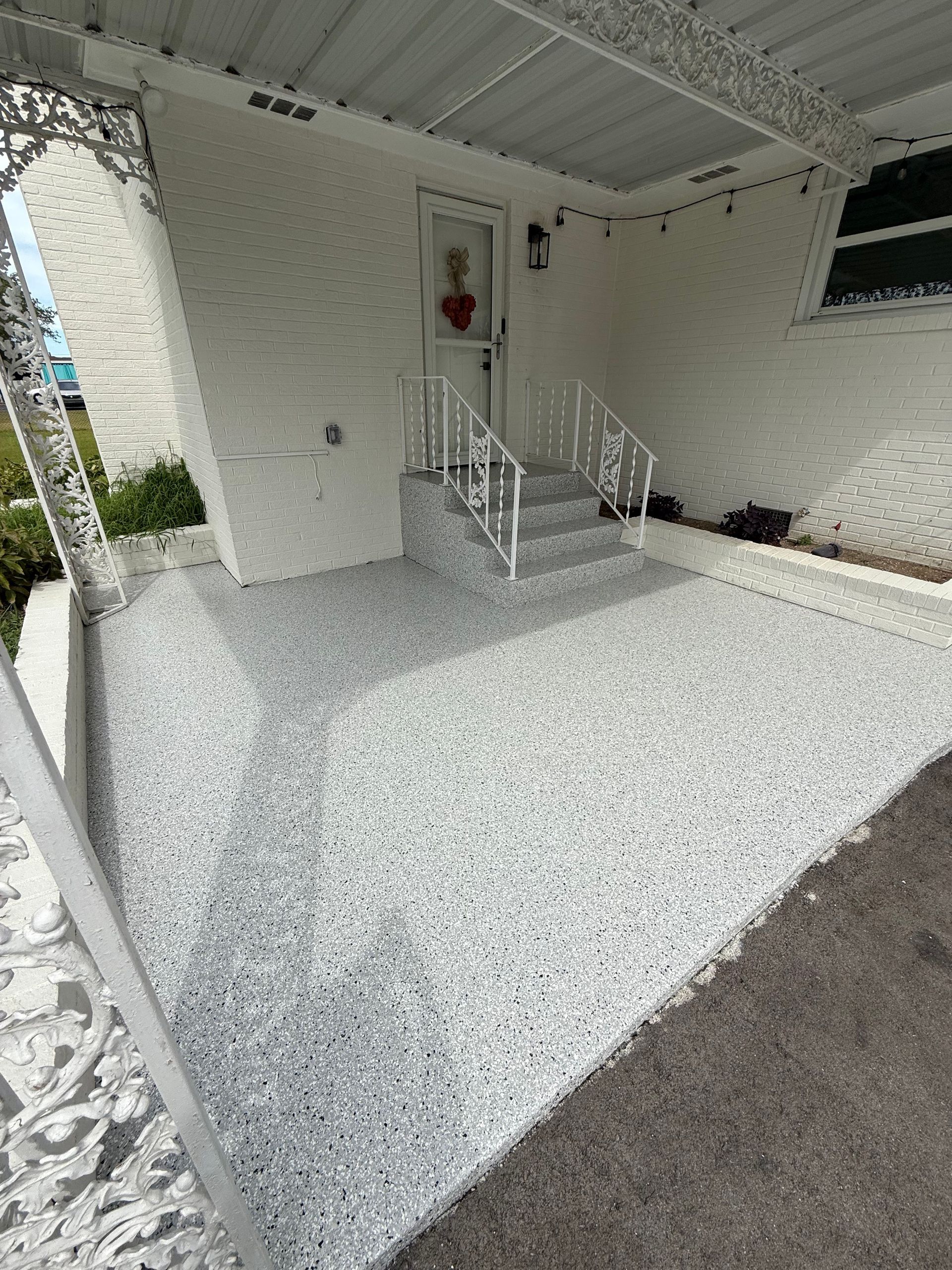 White front porch with steps, railing, and a screened-in area overlooking a gravel yard.
