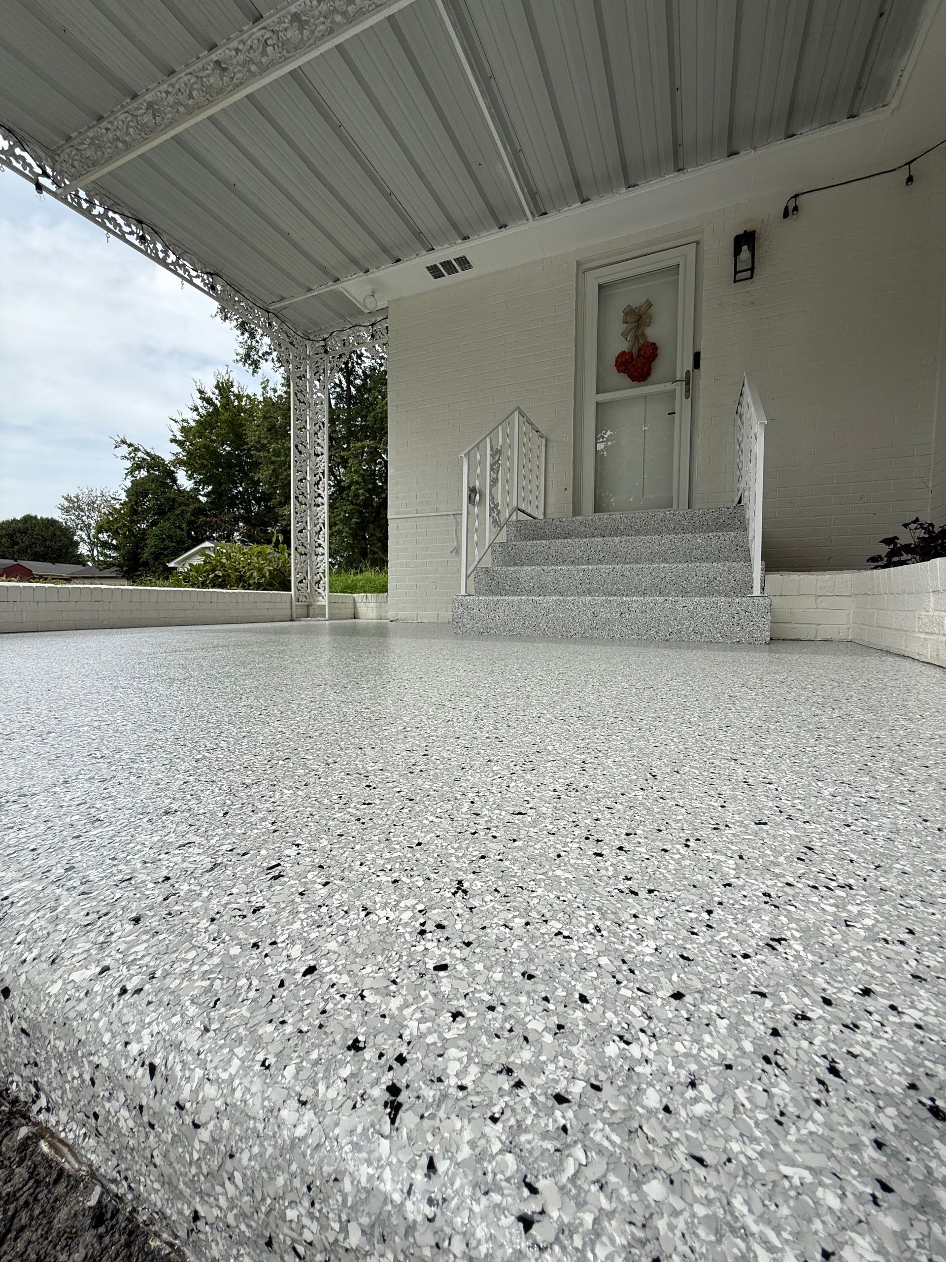 White front porch with stone steps and a red wreath on the door
