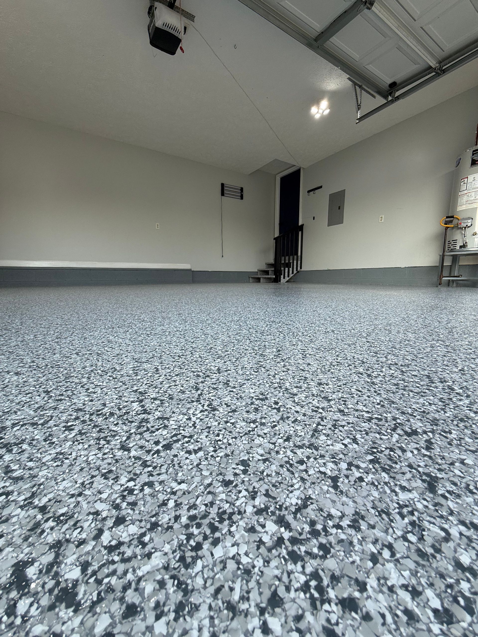 Empty garage interior with speckled epoxy floor and open overhead door, viewed from low angle