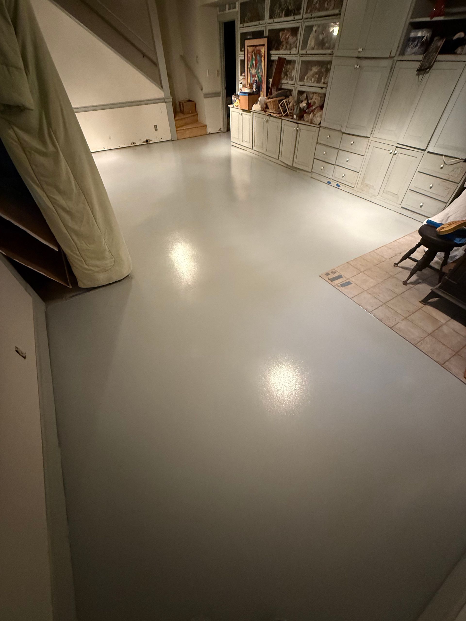 Empty room with glossy white floor, tiled walls, and a chair in the corner.