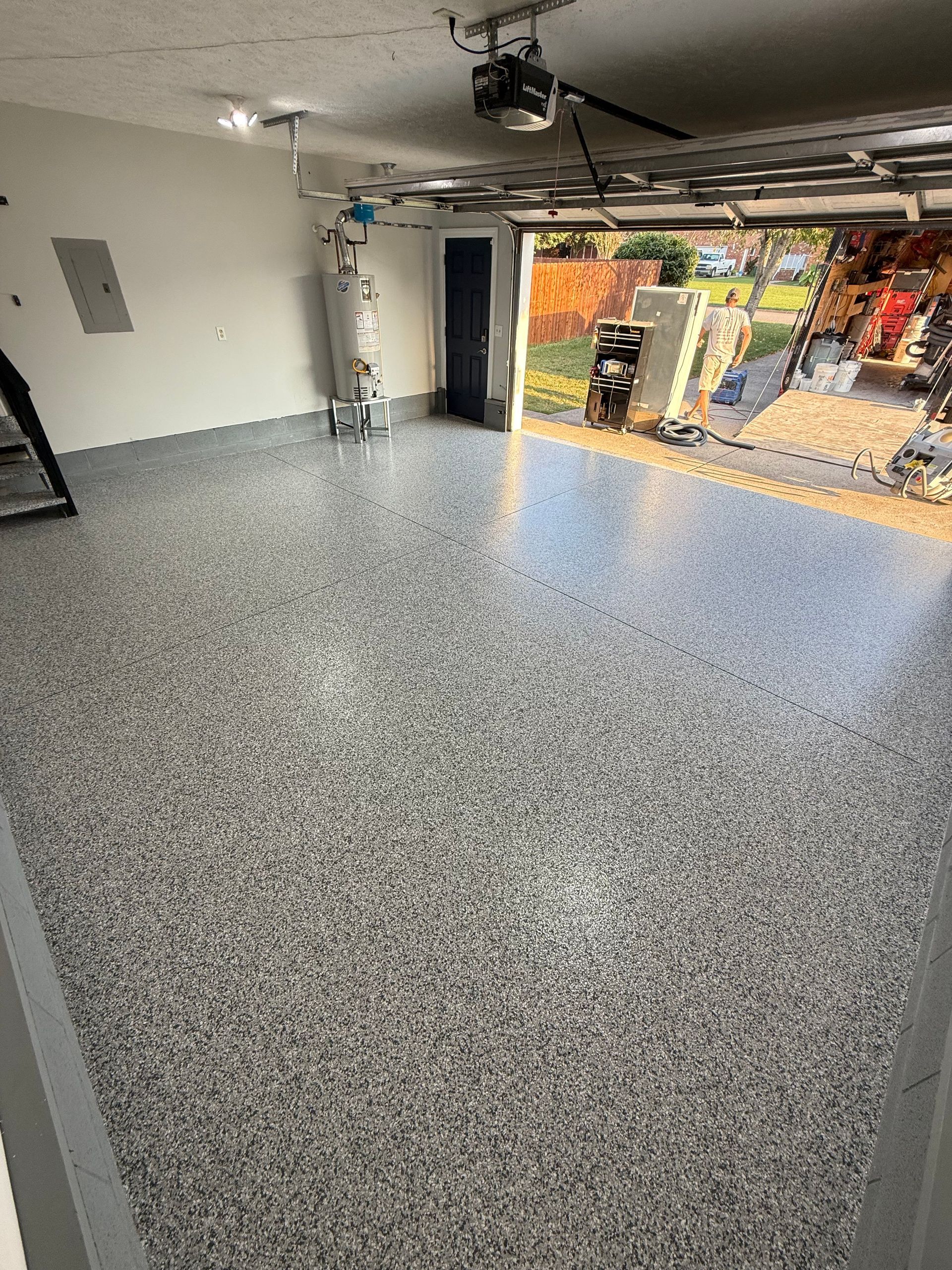 Empty speckled garage floor with an open doorway to a bright outdoor area.