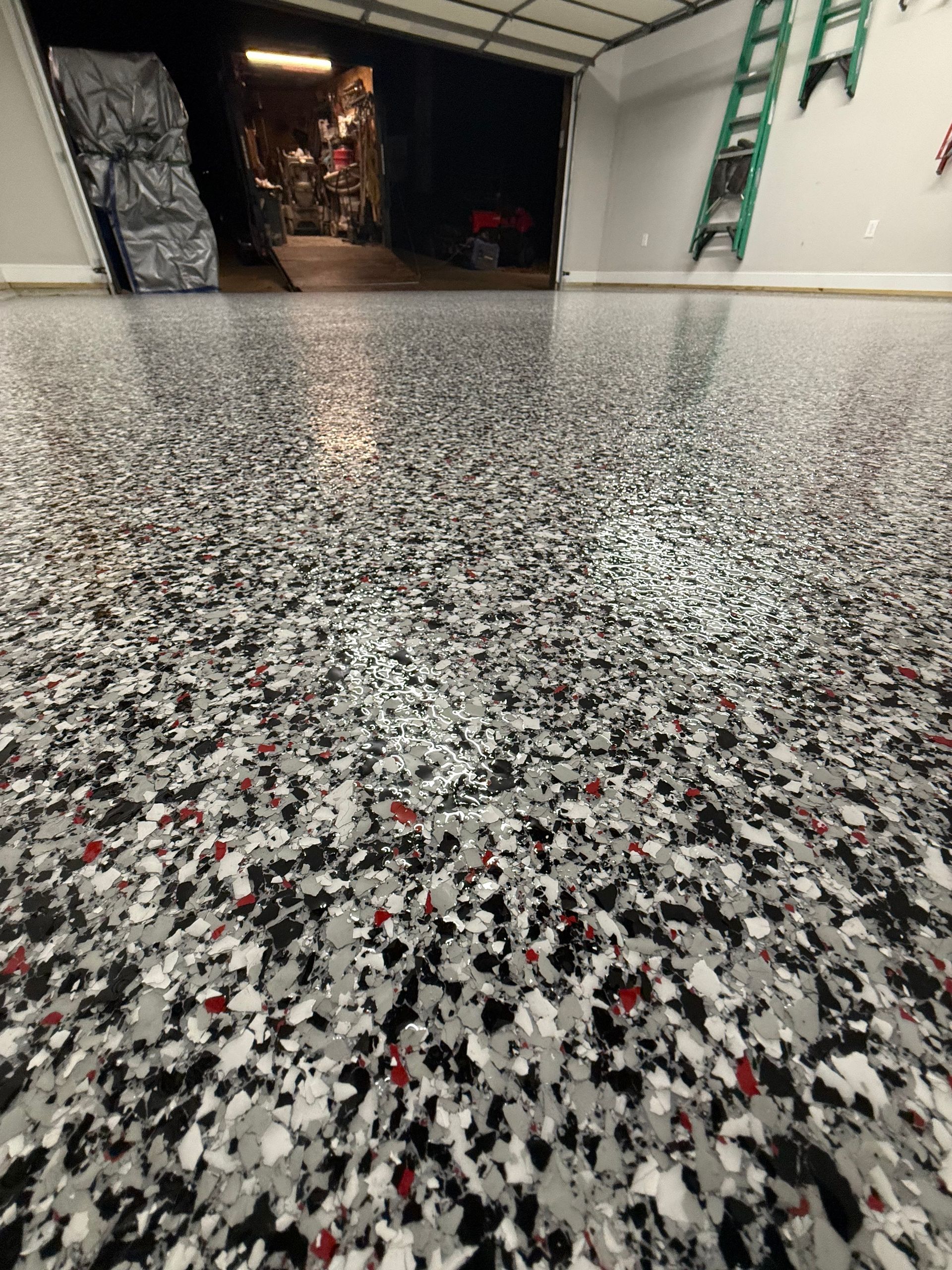 Speckled epoxy floor in an industrial garage with ladders and open storage area in the background